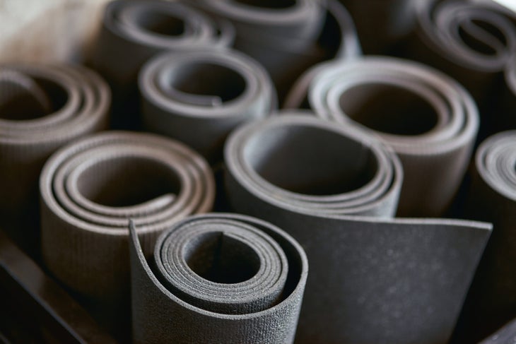 Several black used yoga mats rolled up and stored next to each other.