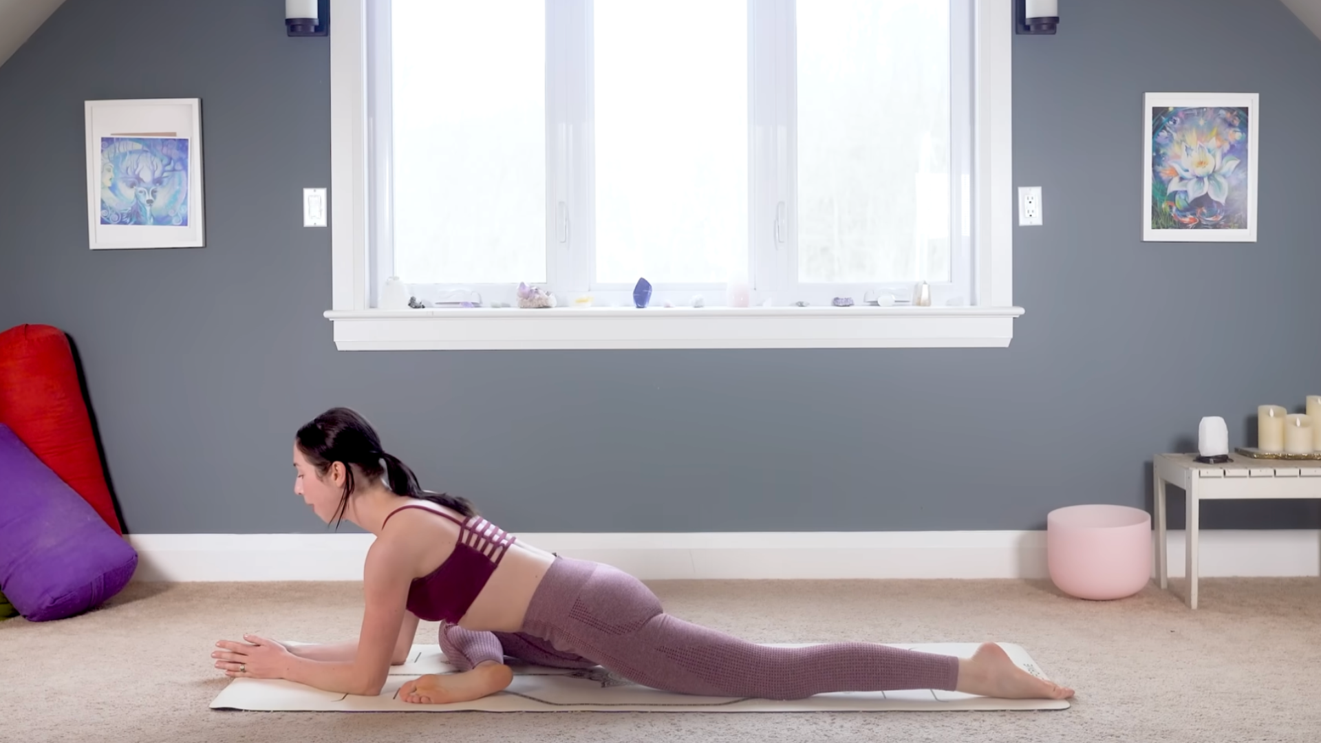 Woman on a yoga mat practicing hip opening stretches including Pigeon on forearms