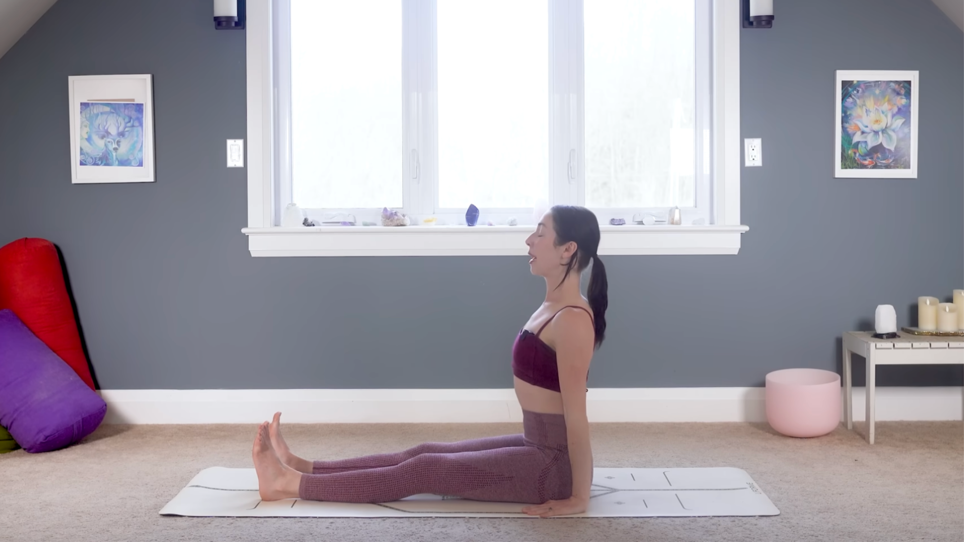 Woman practicing 15-minute yoga by sitting on a mat with her legs straight in front of her