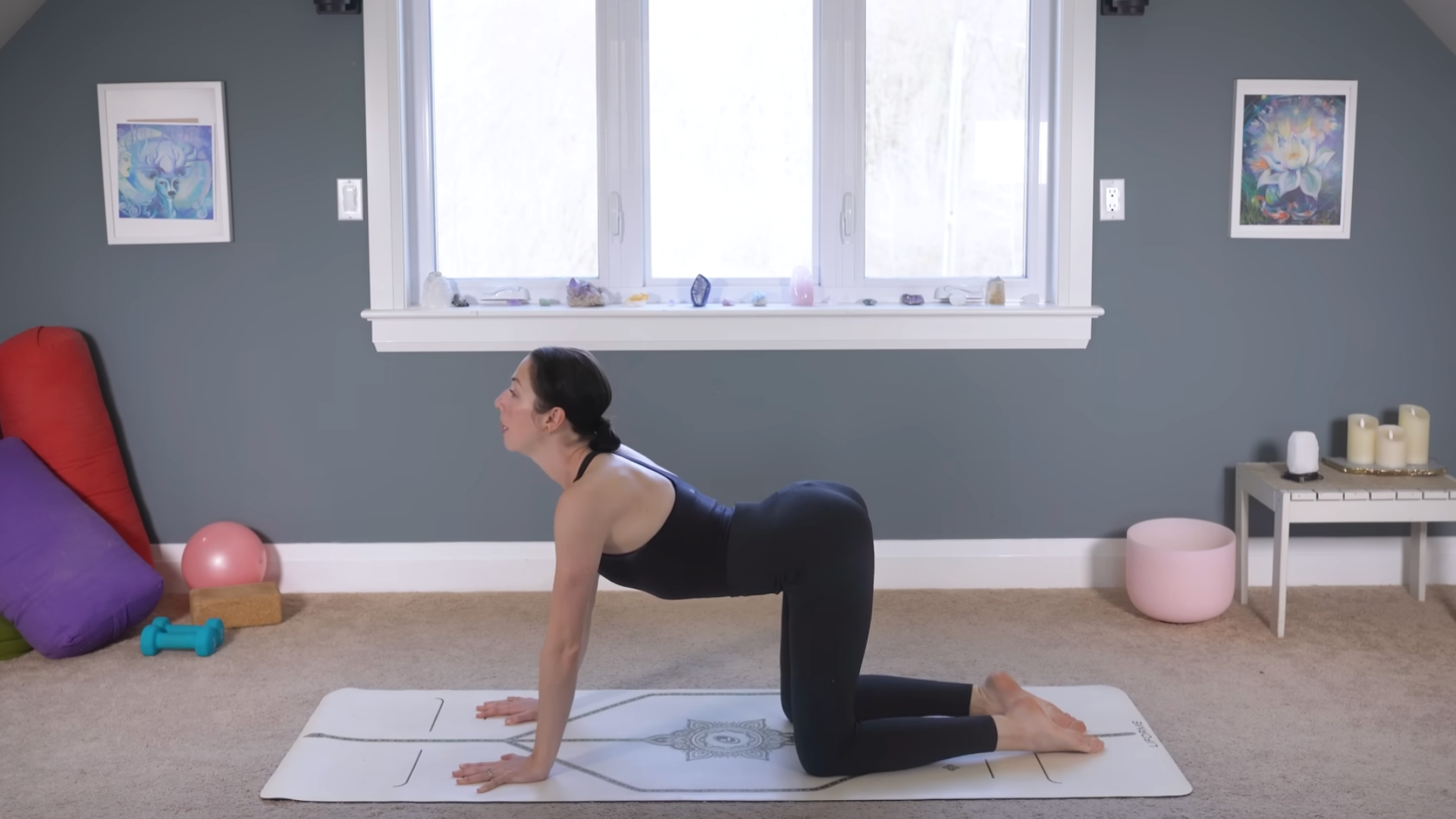 Yoga teacher kneeling on a mat with her back arched