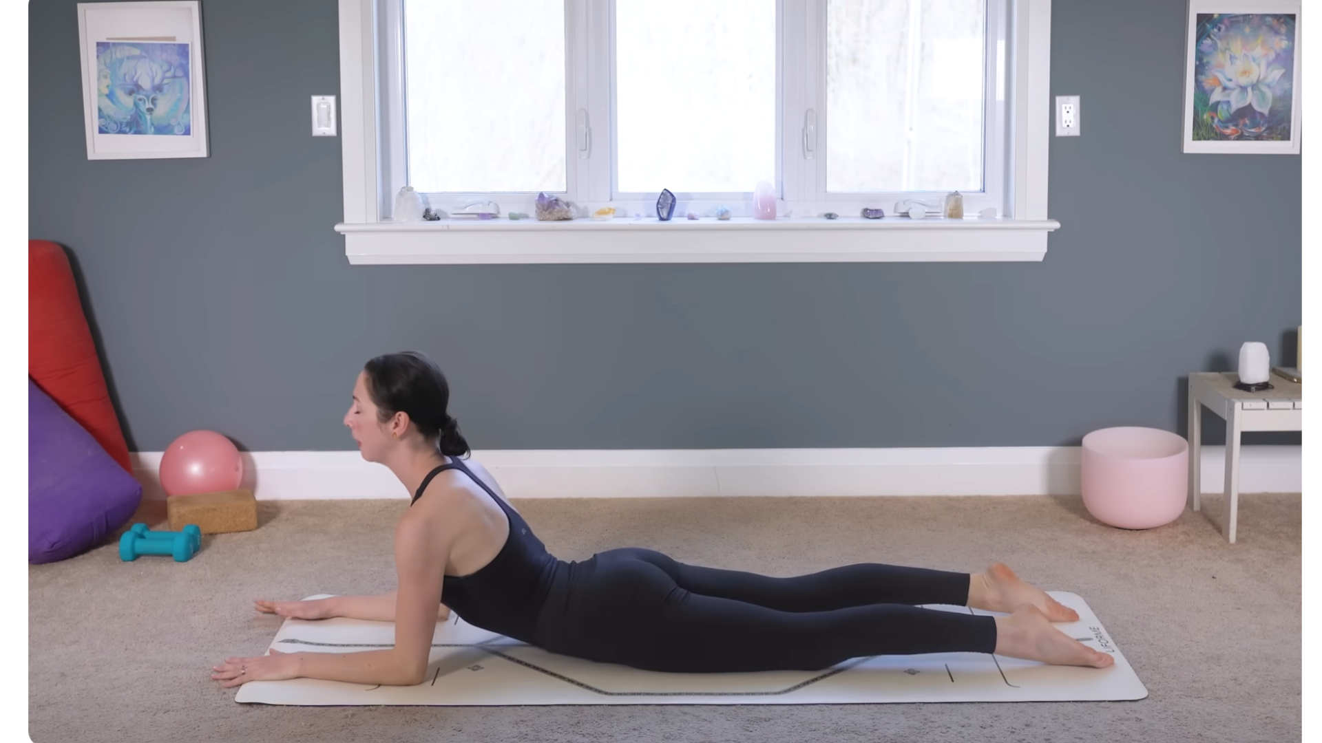 Woman lying belly-down on a yoga mat in Sphinx Pose
