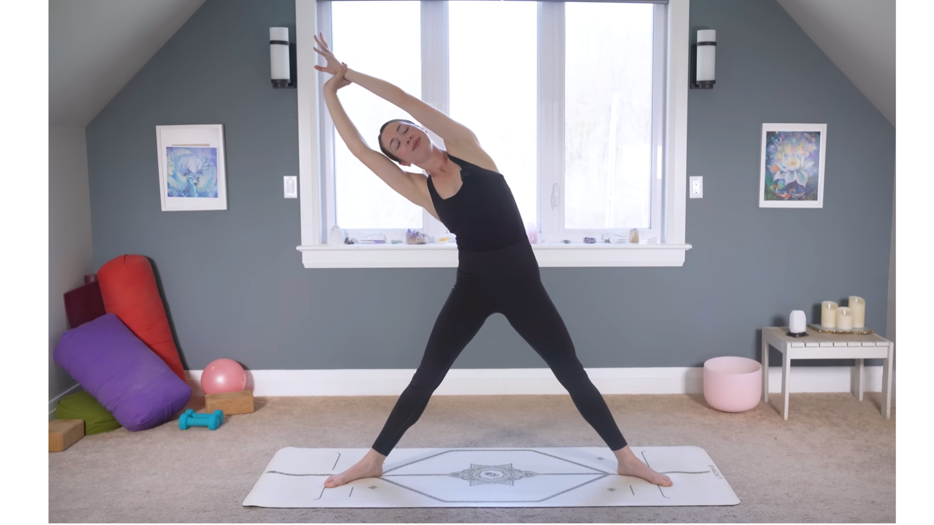 Woman standing on a yoga mat and doing a side stretch by grabbing one wrist and leaning the opposite direction