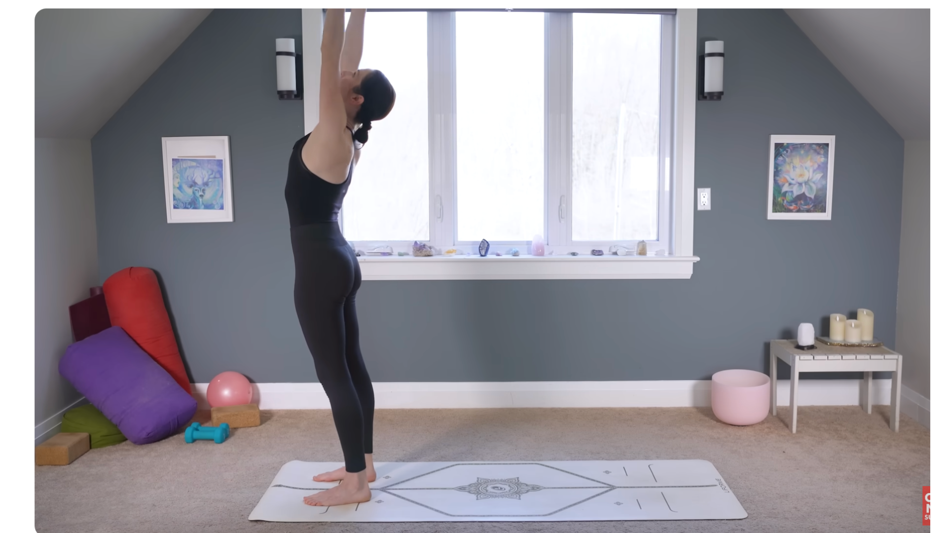Yoga teacher standing on a mat reaching her arms alongside her ears during a 10-minute morning yoga routine