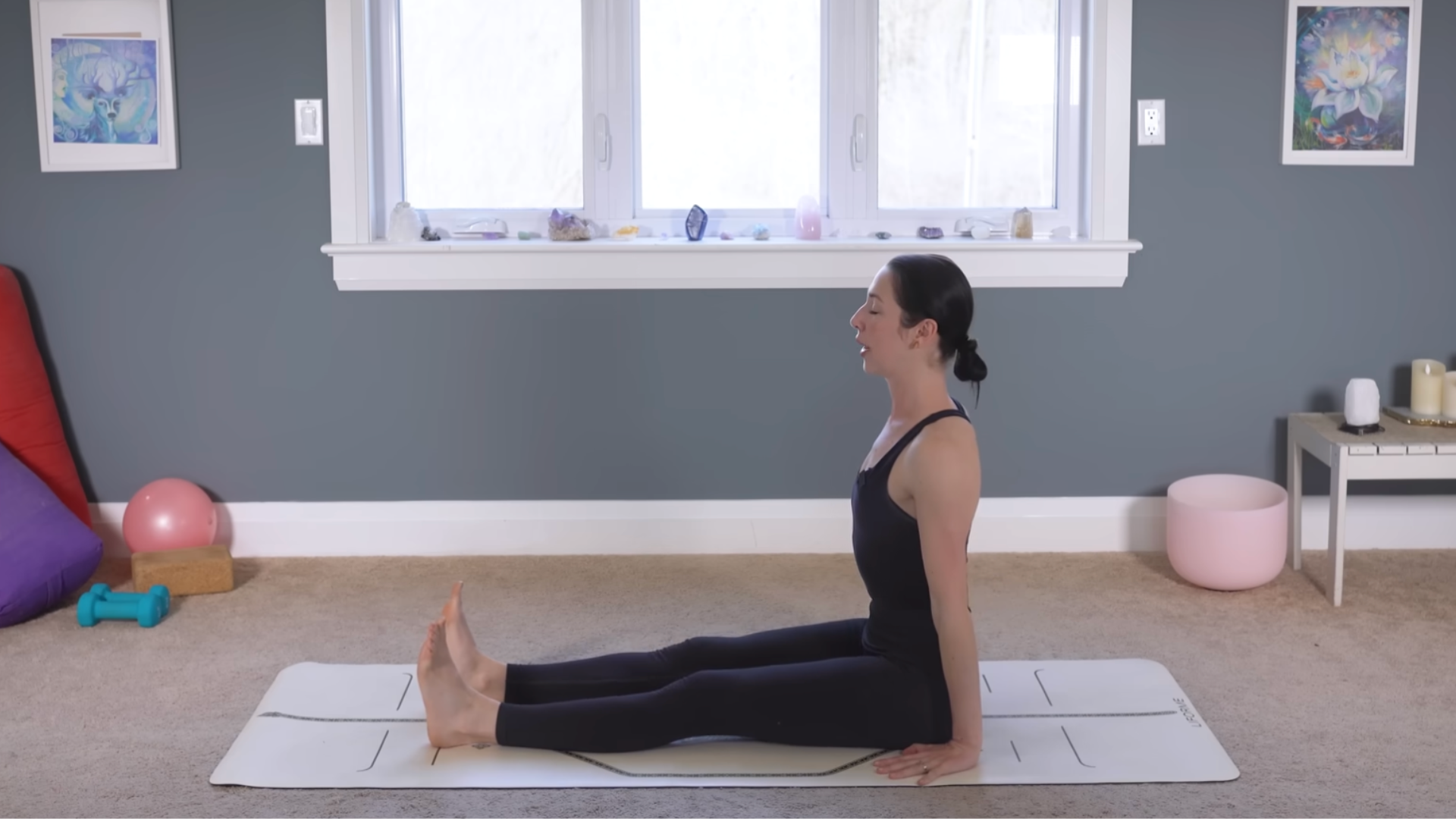 Yoga teacher practicing Staff Pose on a yoga mat