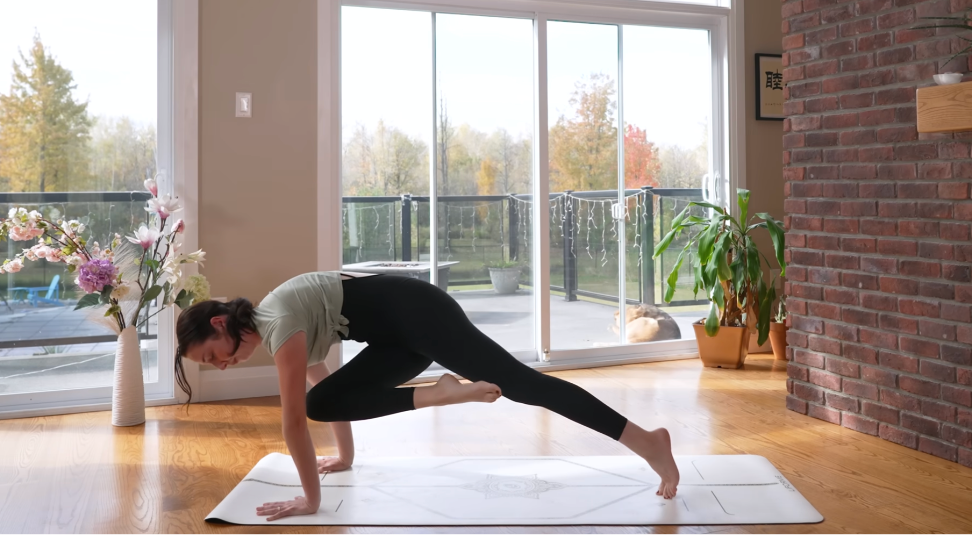 Yoga teacher in a knee-to-elbow pose on a mat