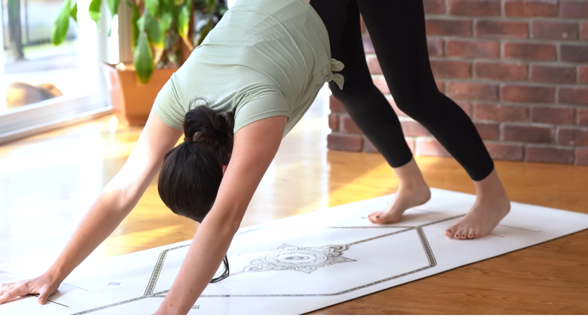Woman practicing Down Dog with her hands and feet on a mat during a 15-minute morning yoga flow