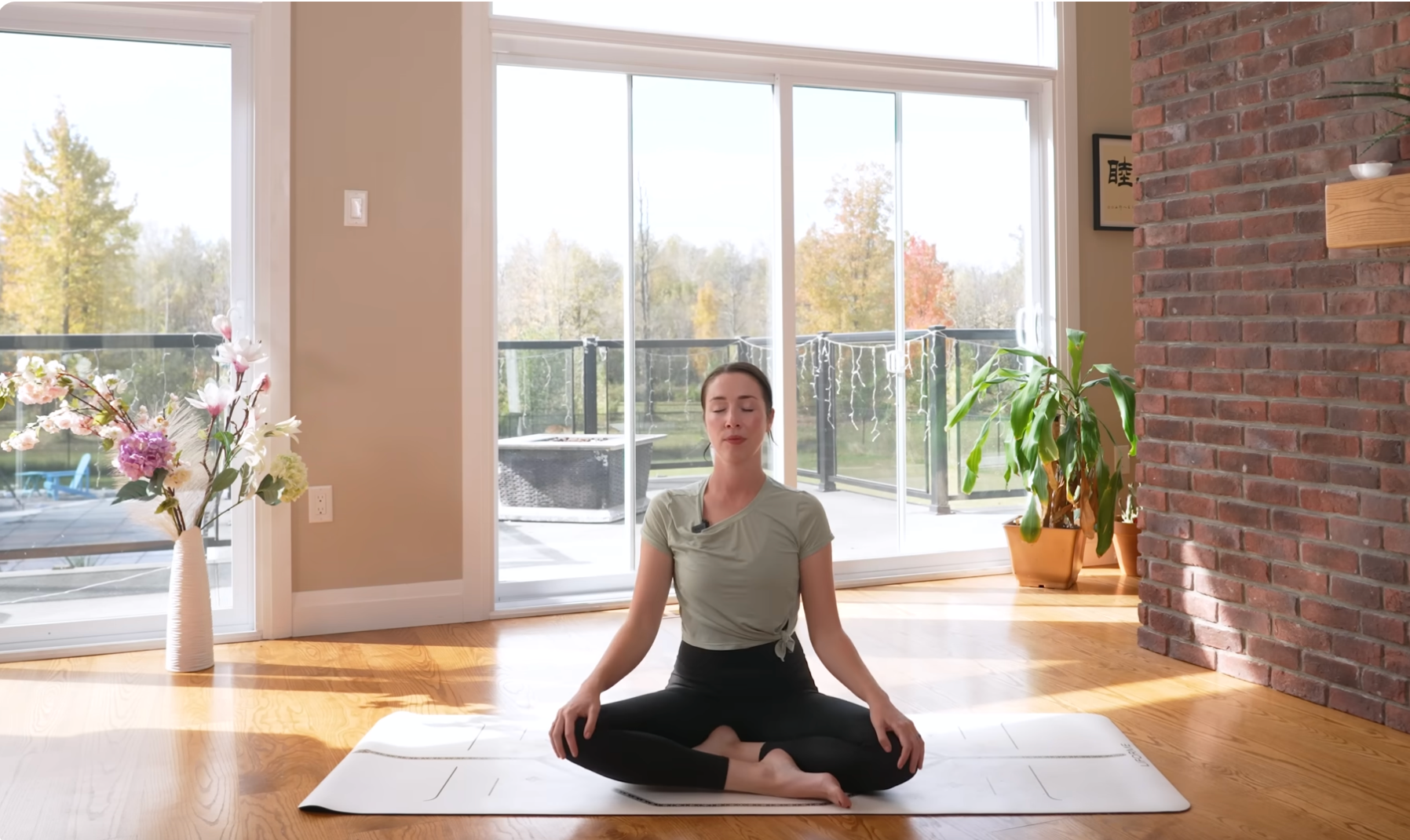 Woman sitting cross-legged on a mat following a 15-minute morning yoga for stretching and strengthening class