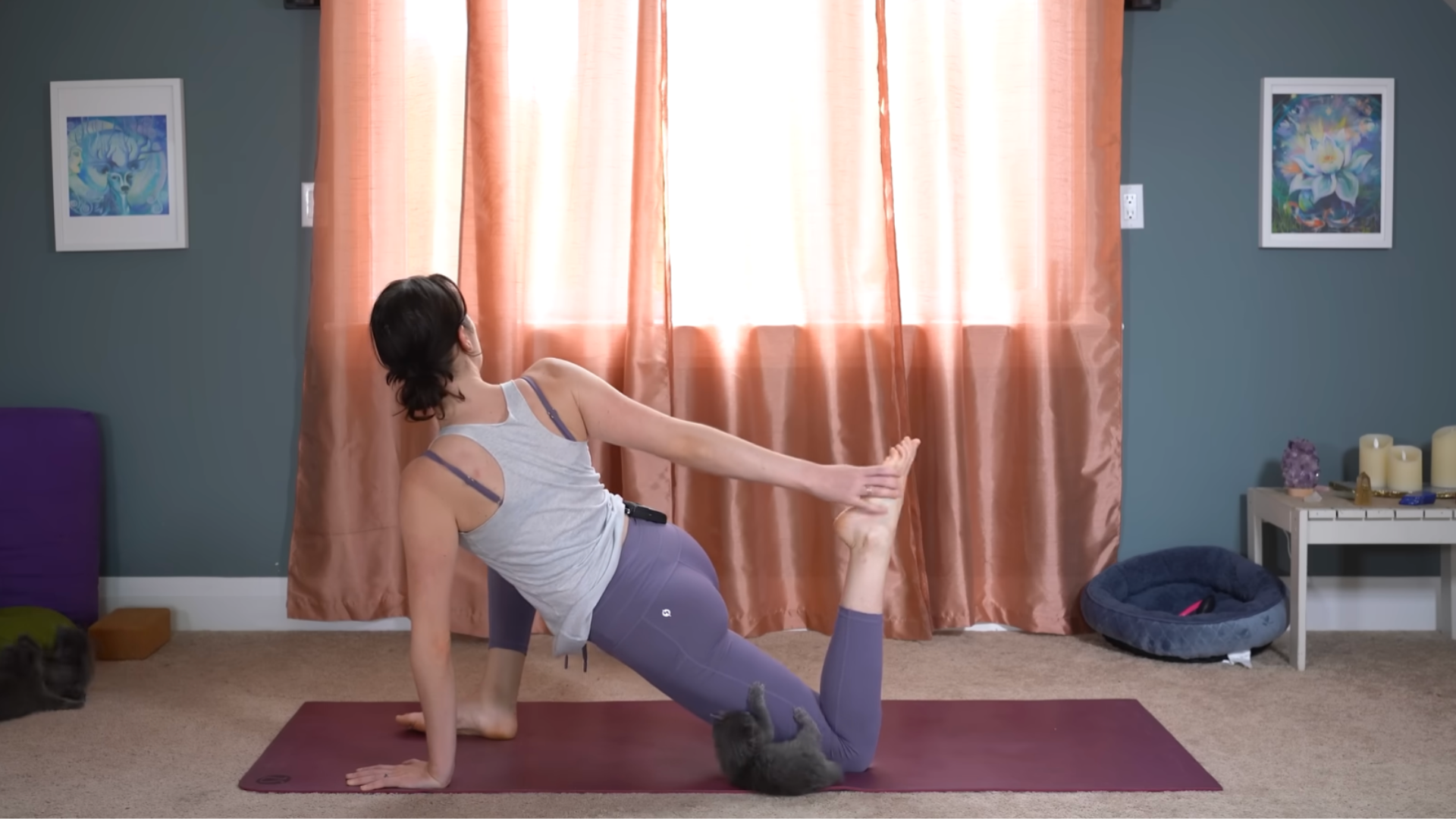 Yoga teacher kneeling on a yoga mat in a low lunge twist while reaching behind for her back foot to draw it toward her hips in a full-body stretch