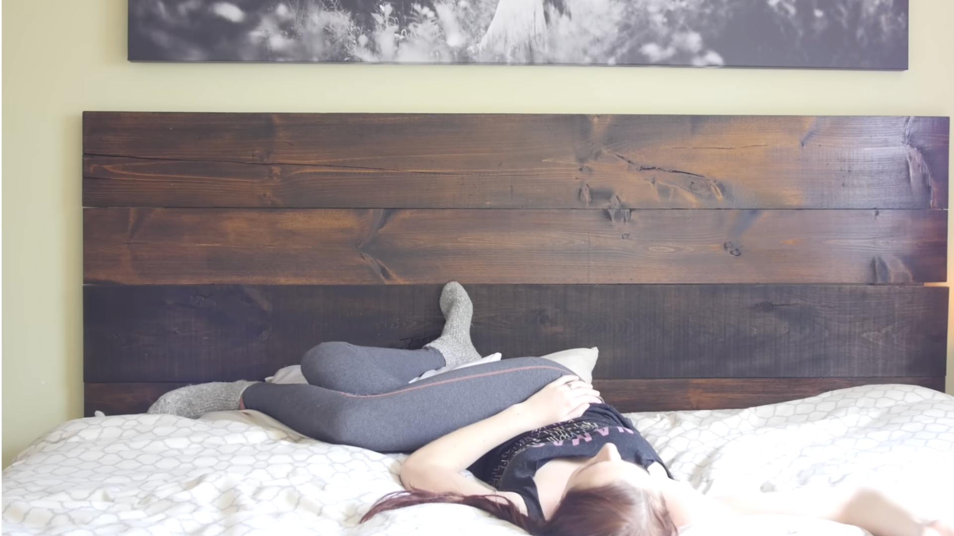 Yoga teacher lying in bed in a reclined twist practicing yoga for sleep