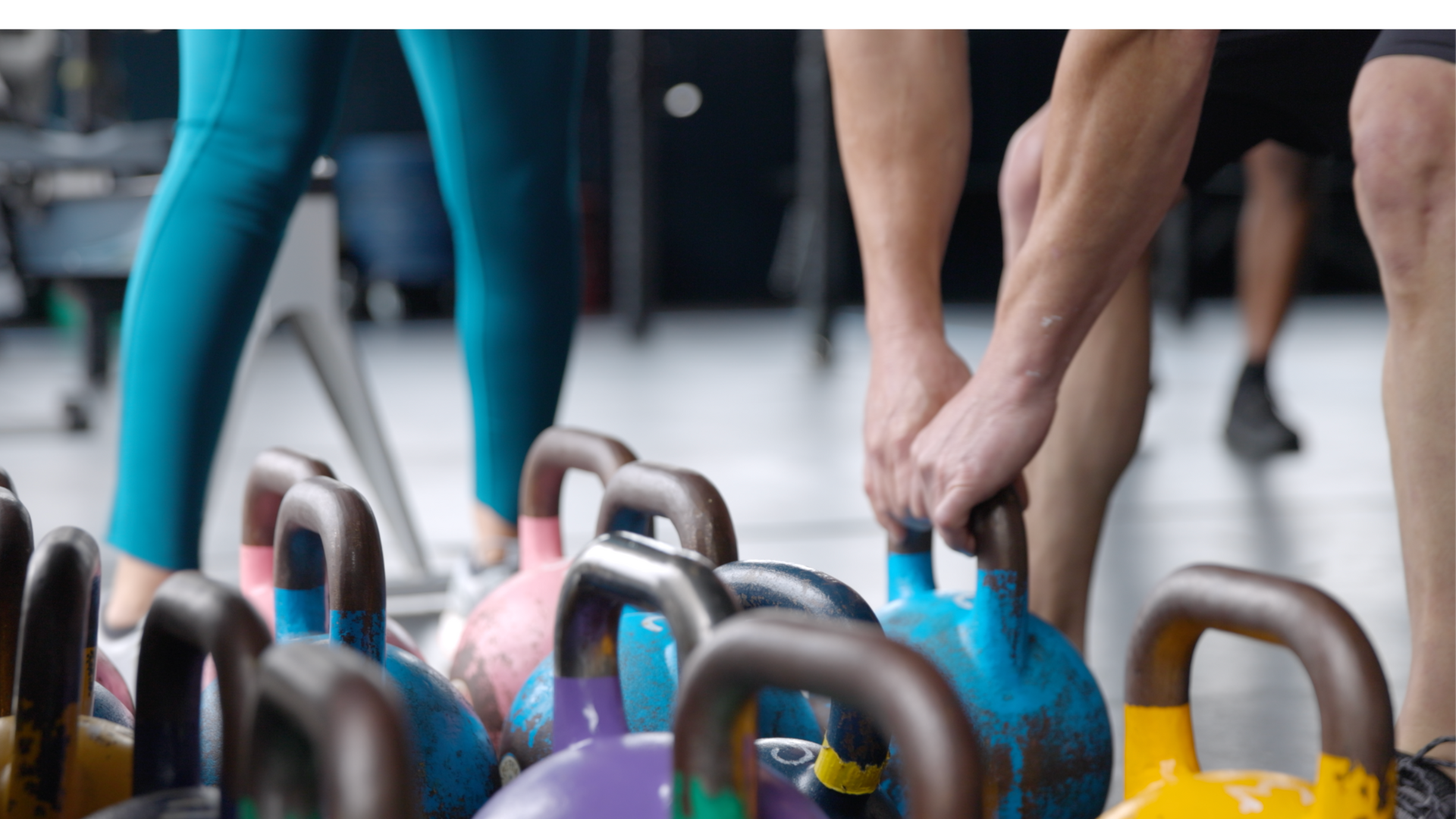 Gym goers lifting kettlebells at a gym with yoga classes