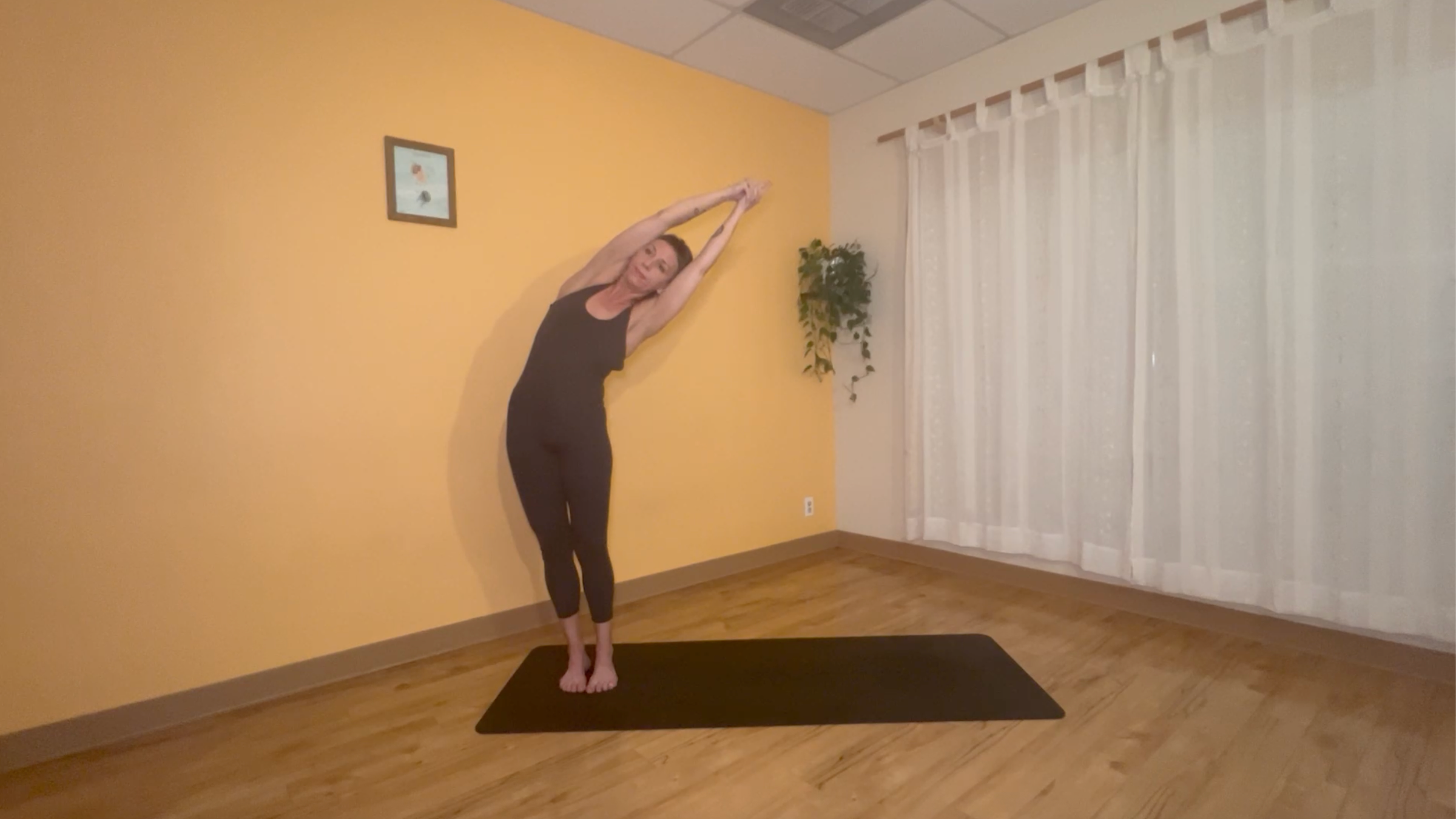 yoga teacher standing on mat practicing moon salutations in side bend