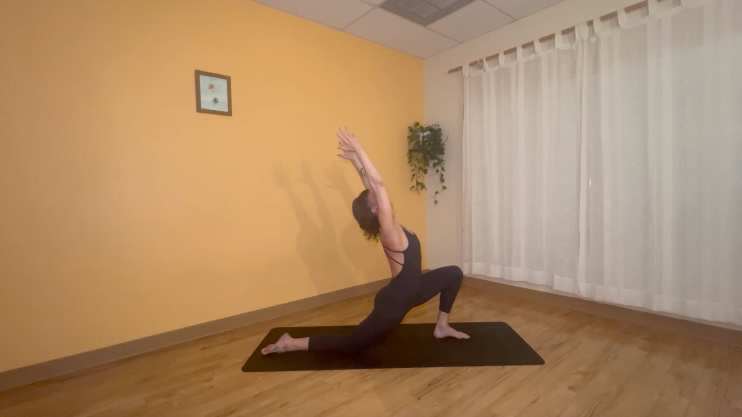 yoga teacher standing on mat practicing moon salutations in low lunge