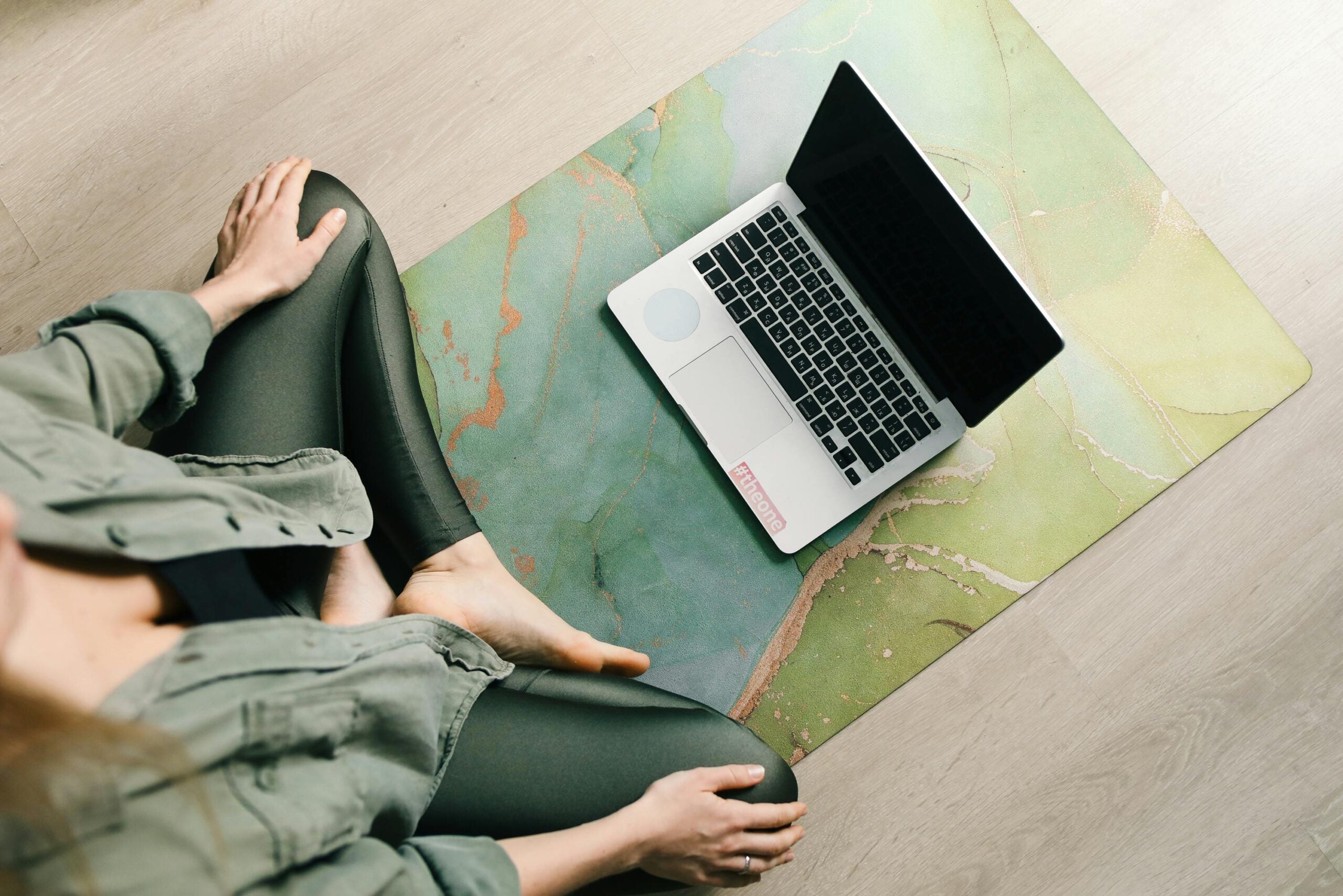 Woman on yoga mat with open laptop