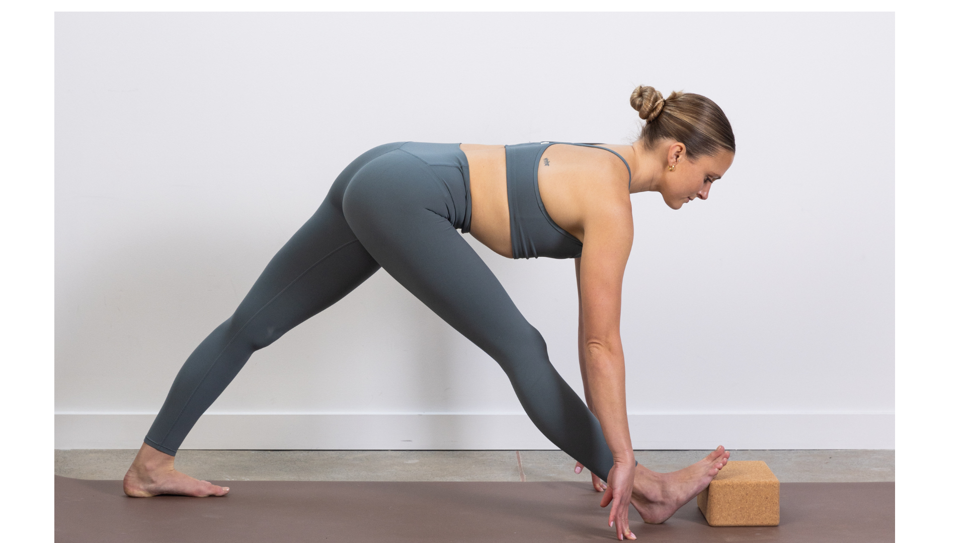 Yoga teacher in Pyramid Pose with a block beneath her front foot