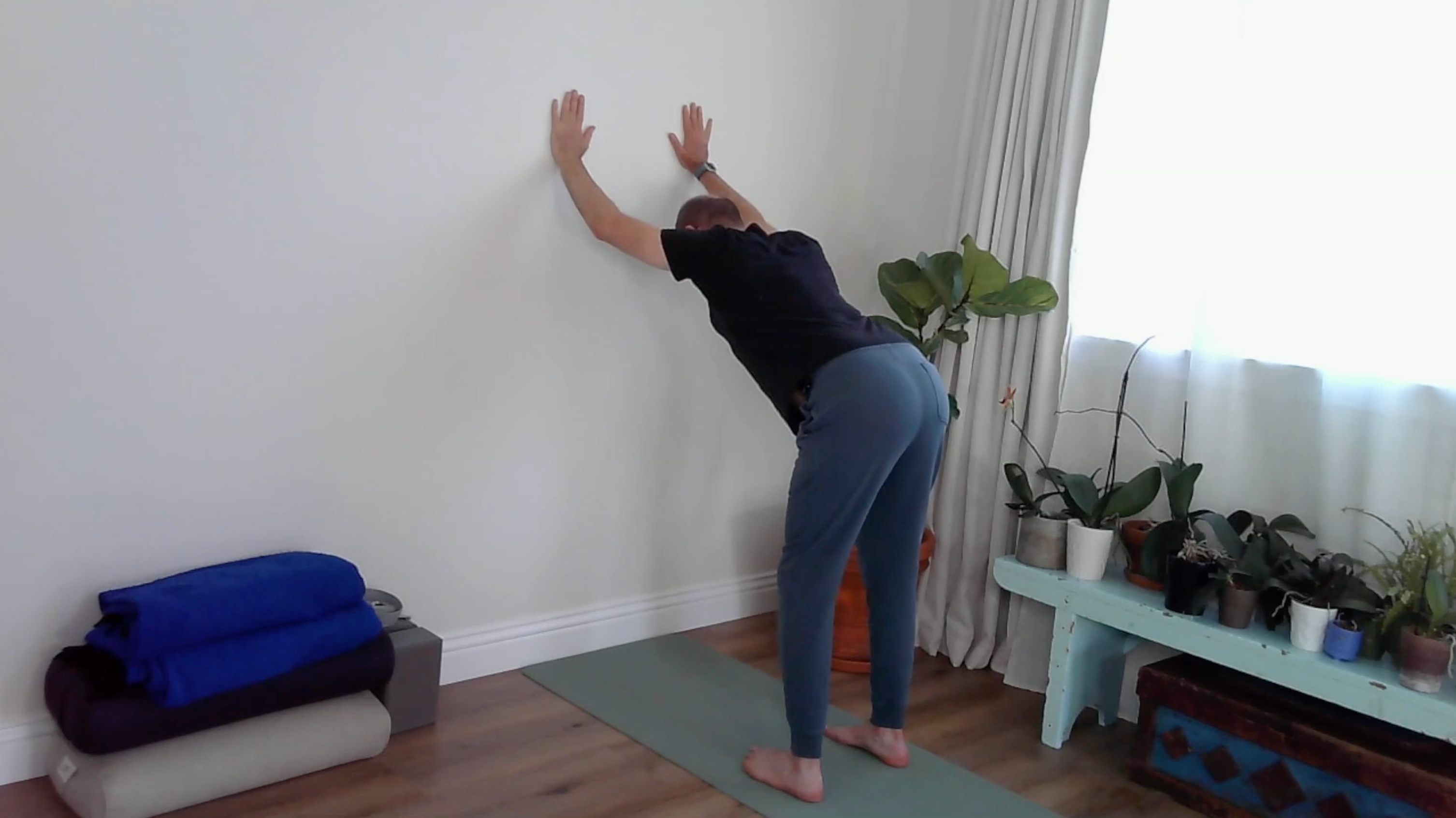 A yoga teacher practicing wall yoga in wall Downward-Facing Dog
