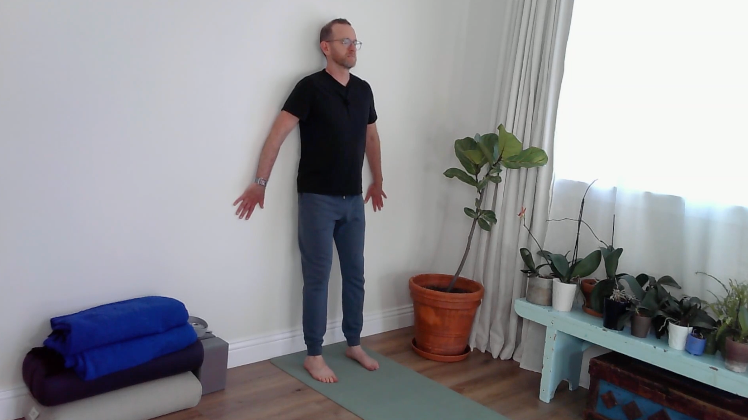 A yoga teacher practicing wall yoga in Mountain Pose