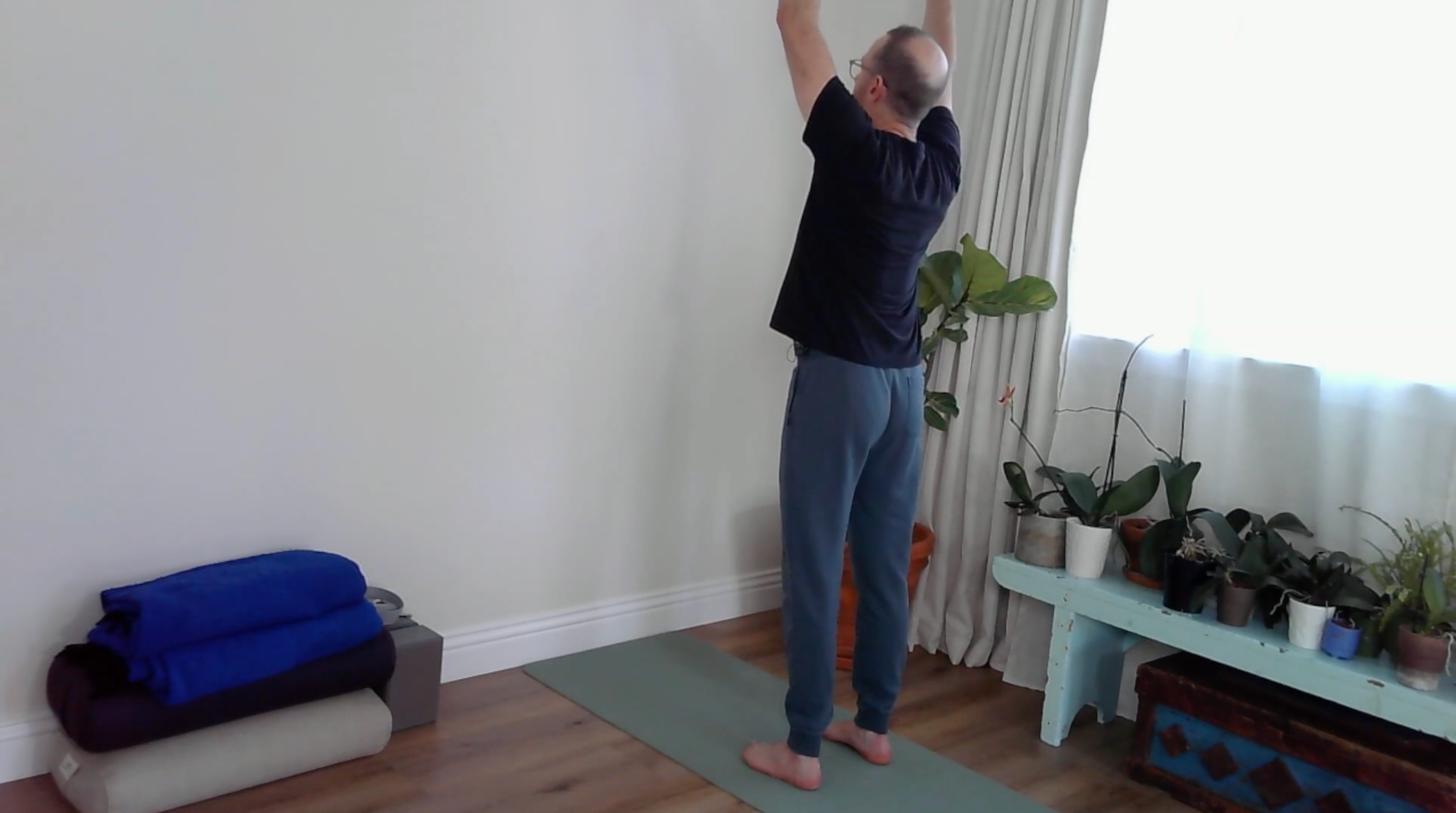 A yoga teacher practicing wall yoga in an Upward Salute
