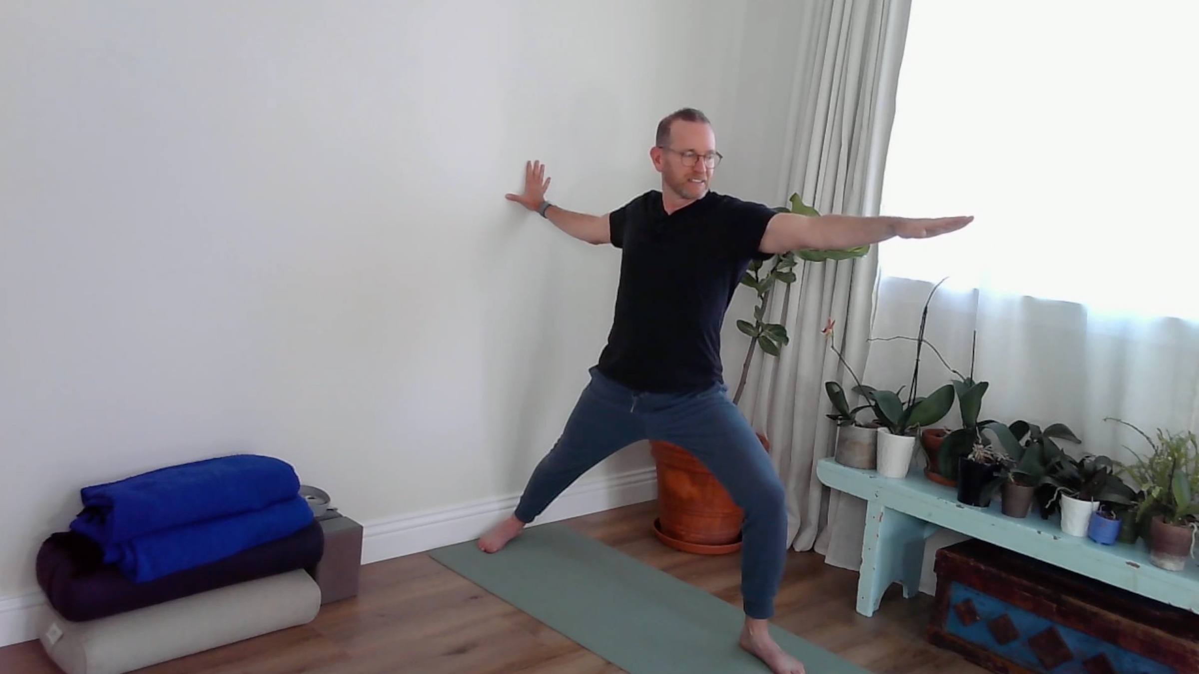 A yoga teacher practicing wall yoga in Warrior II