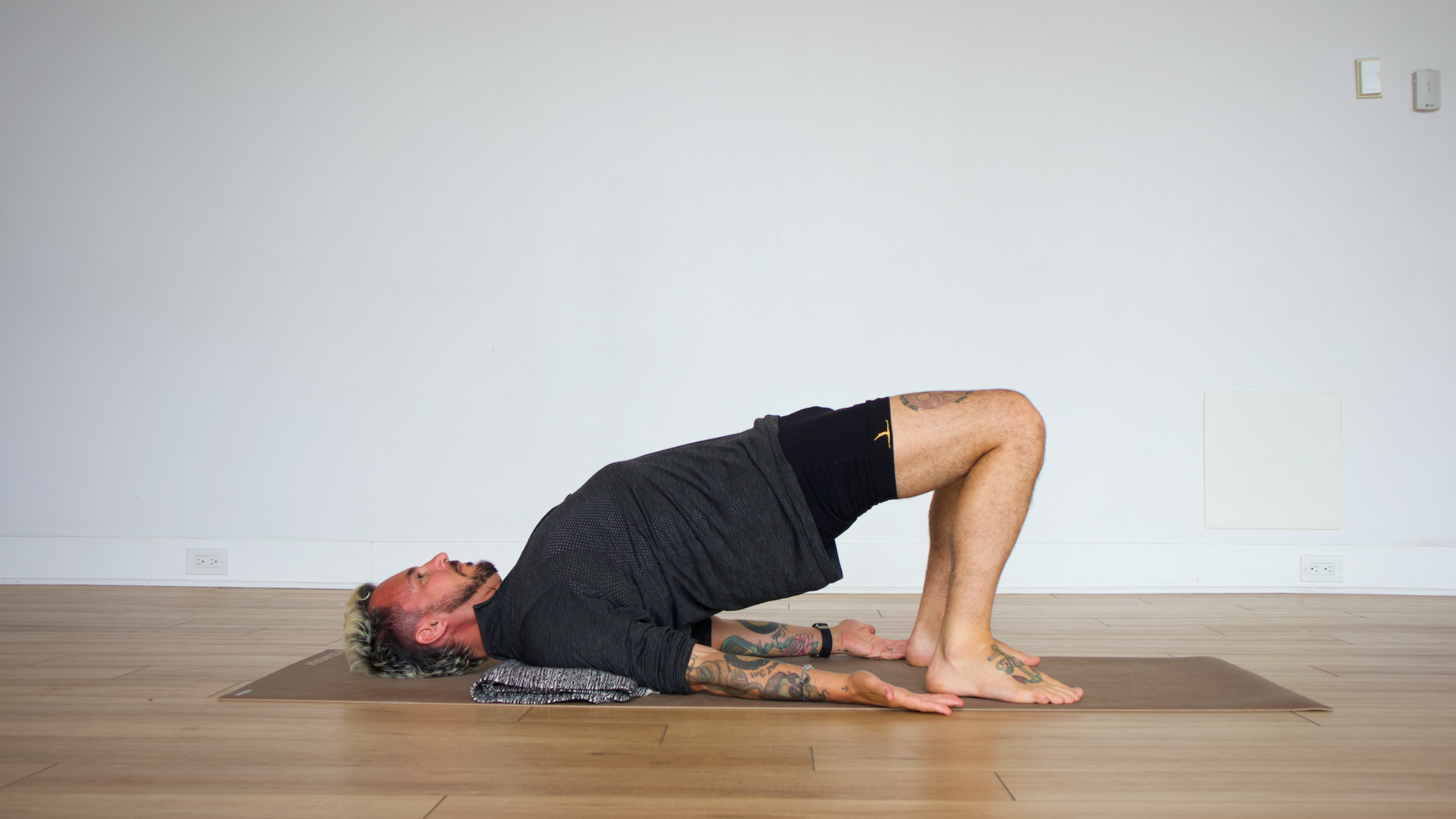Man in bridge pose with blanket on yoga mat