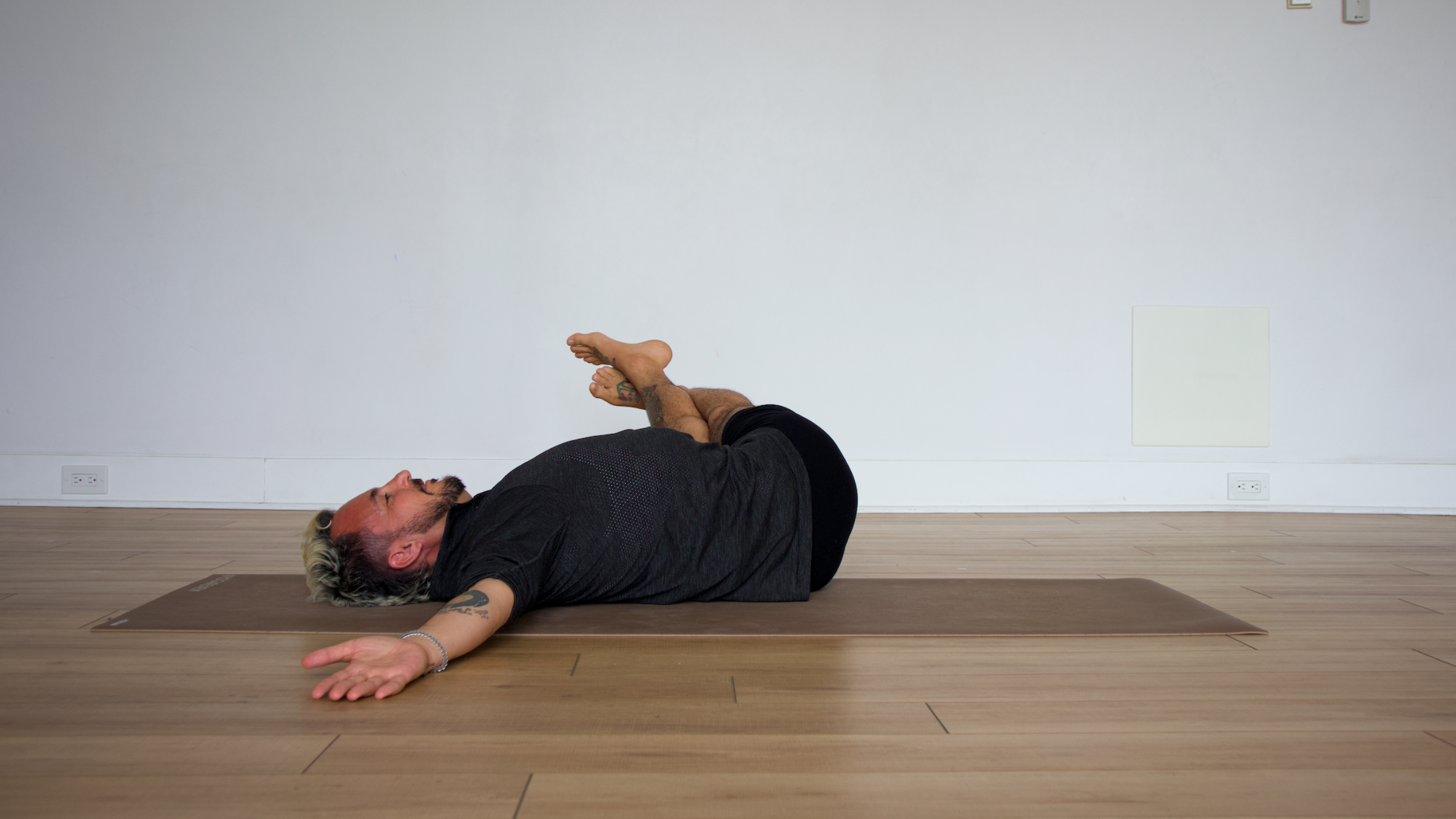 man in reclined revolved belly pose on yoga mat