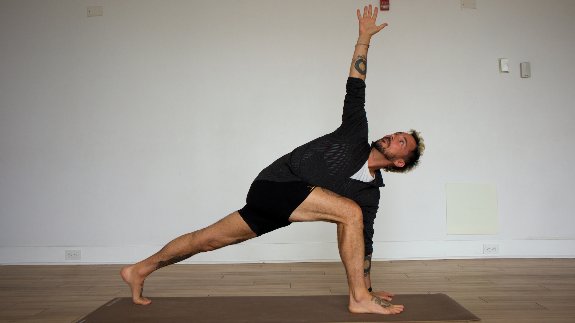 Man in revolved side angle pose on yoga mat