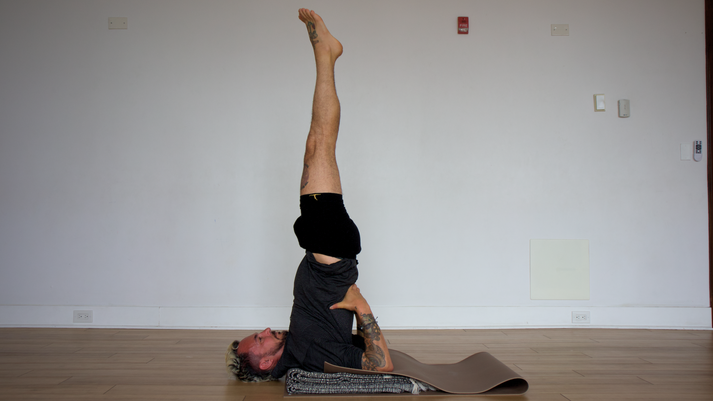 man in shoulderstand pose on yoga mat