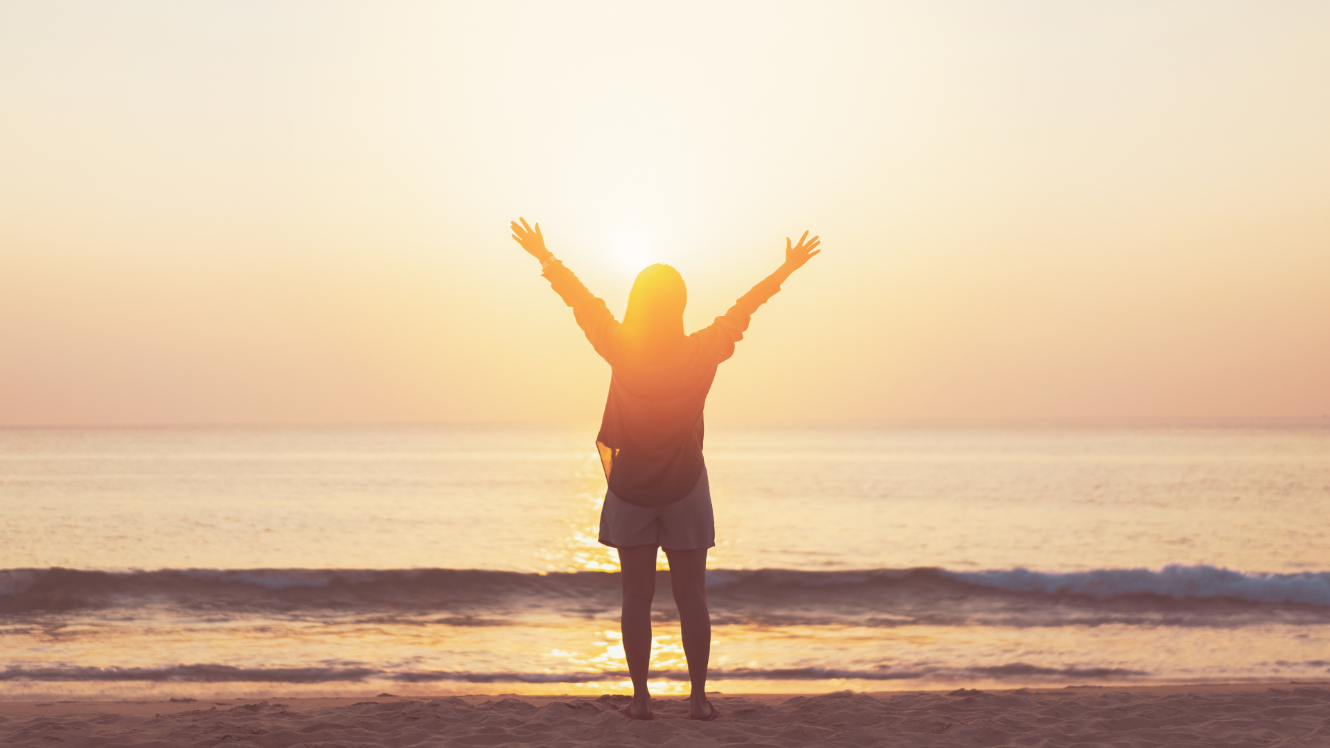 Woman standing on the beach at sundown contemplating Jupiter in Cancer 2025.