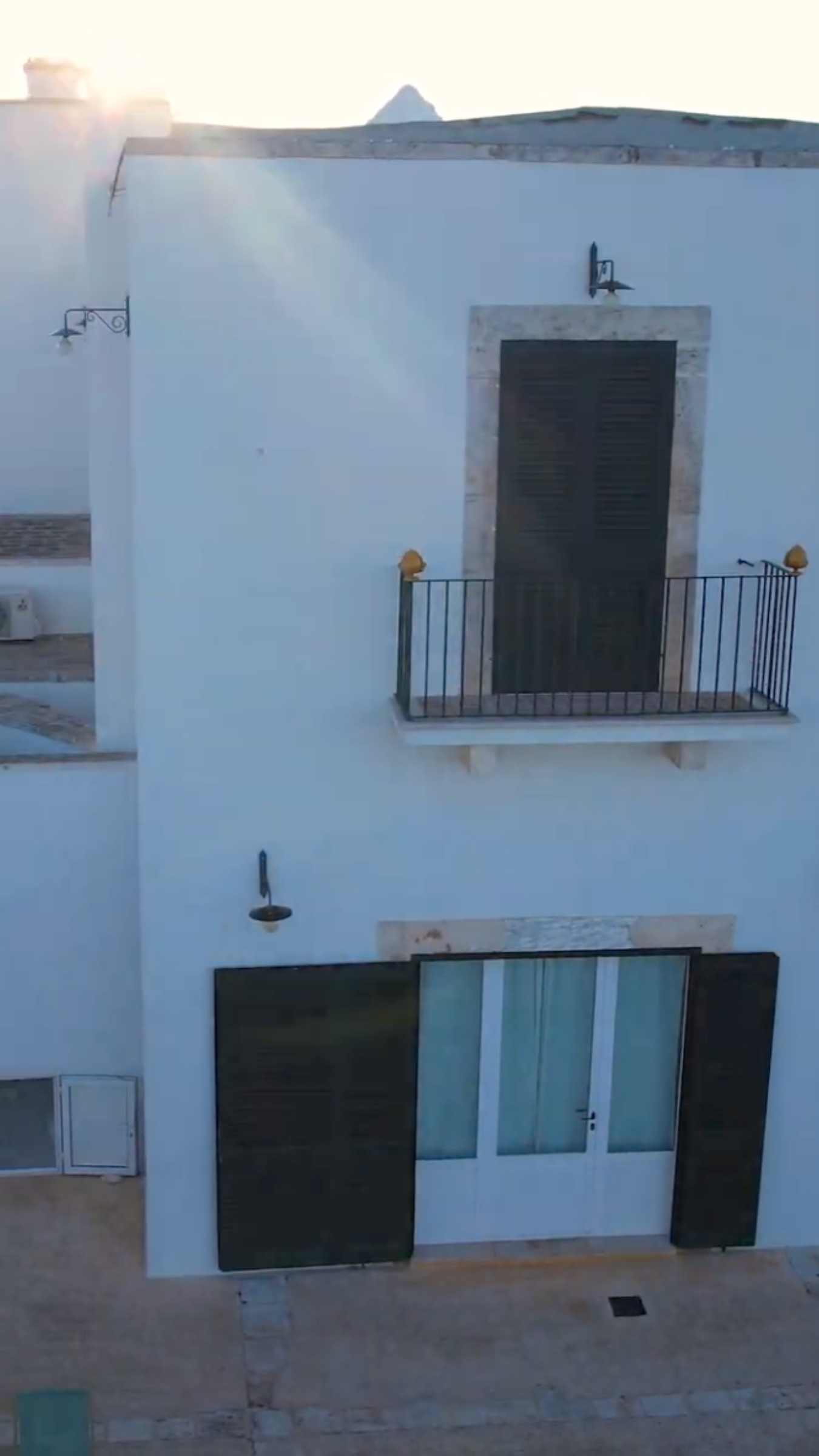 exterior of white two-story building with black shutters and balcony iron