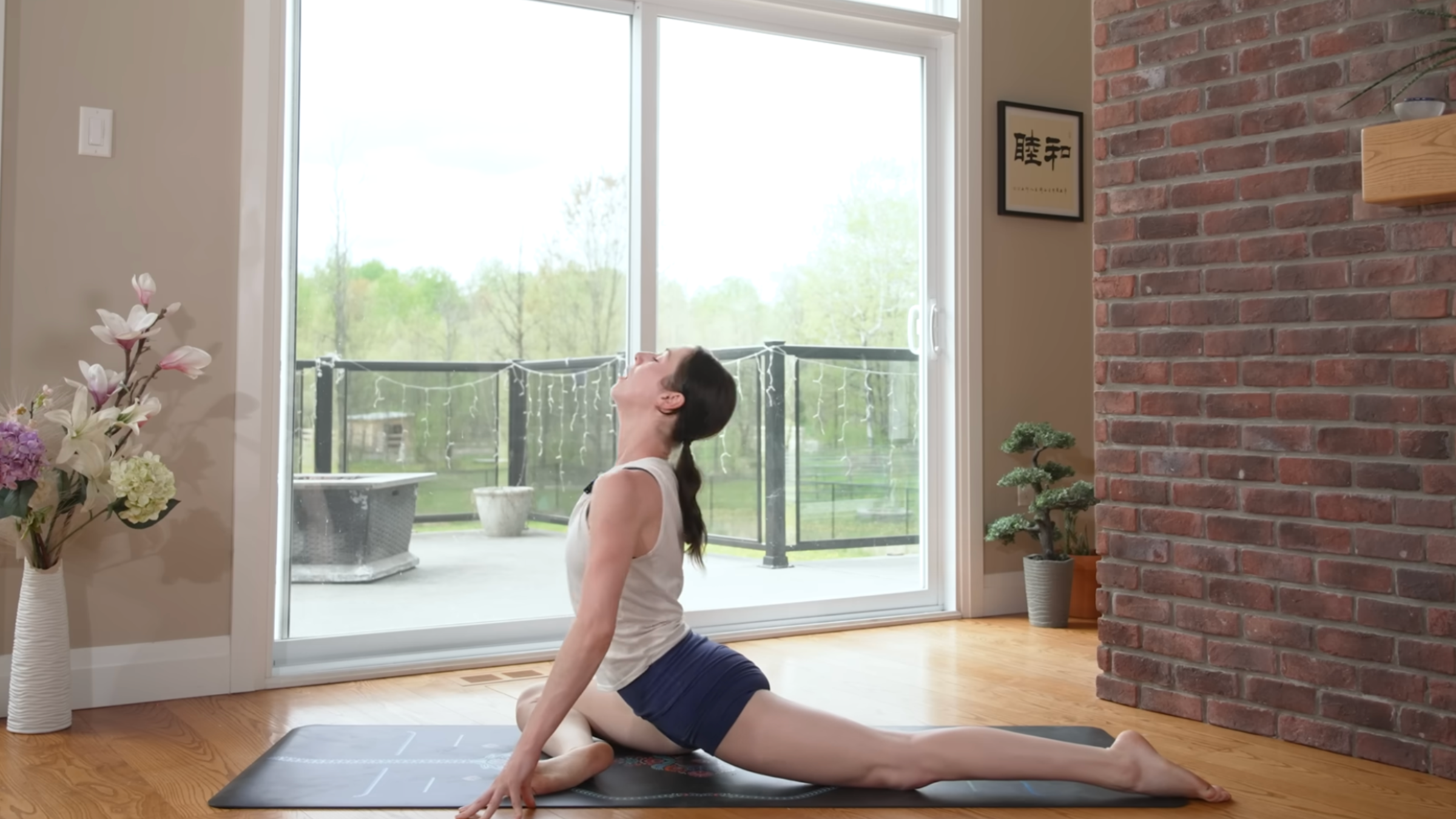 woman in pigeon pose on yoga mat in home