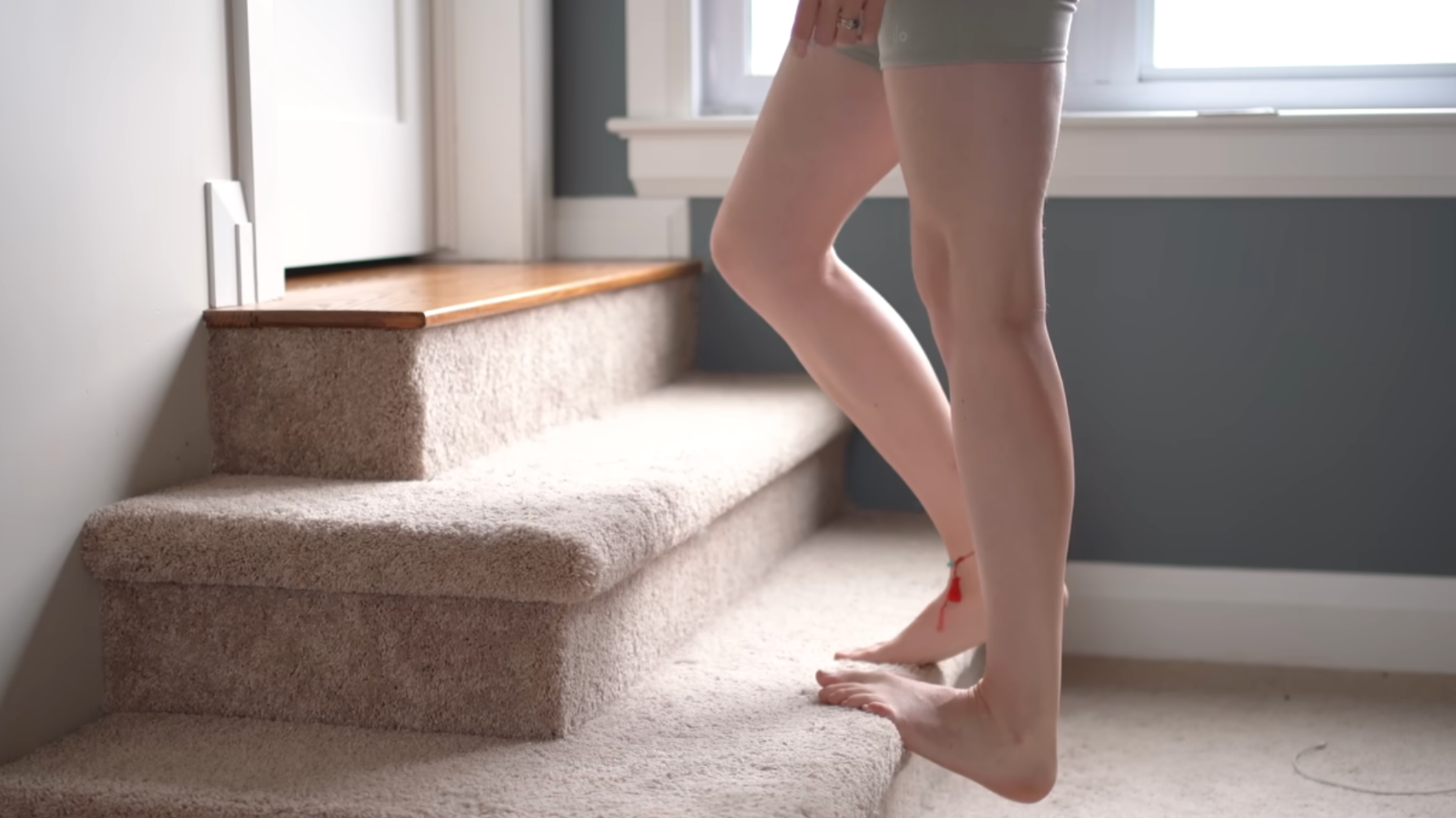 woman's legs on carpeted stairs with one calf being stretched