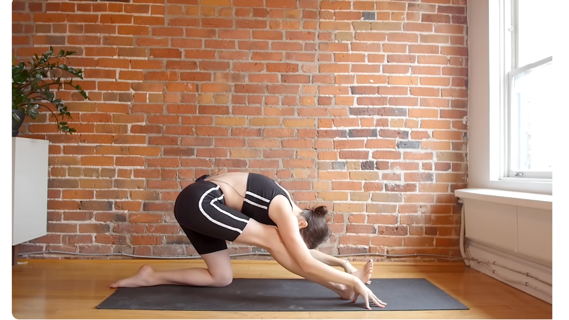Yoga teacher kneeling on a mat in Half Splits for a hamstring stretch by leaning her chest forward toward her front thigh