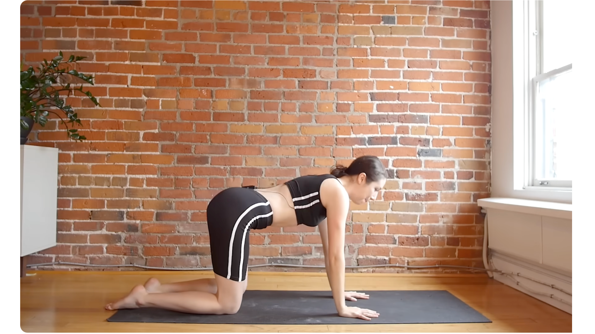 Yoga teacher kneeling on a mat in Tabletop while practicing ankle rolls