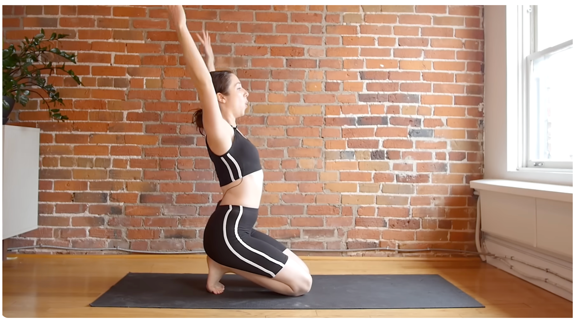 Yoga teacher kneeling on a mat and reaching her arms overhead during a 10-minute morning yoga stretches routine