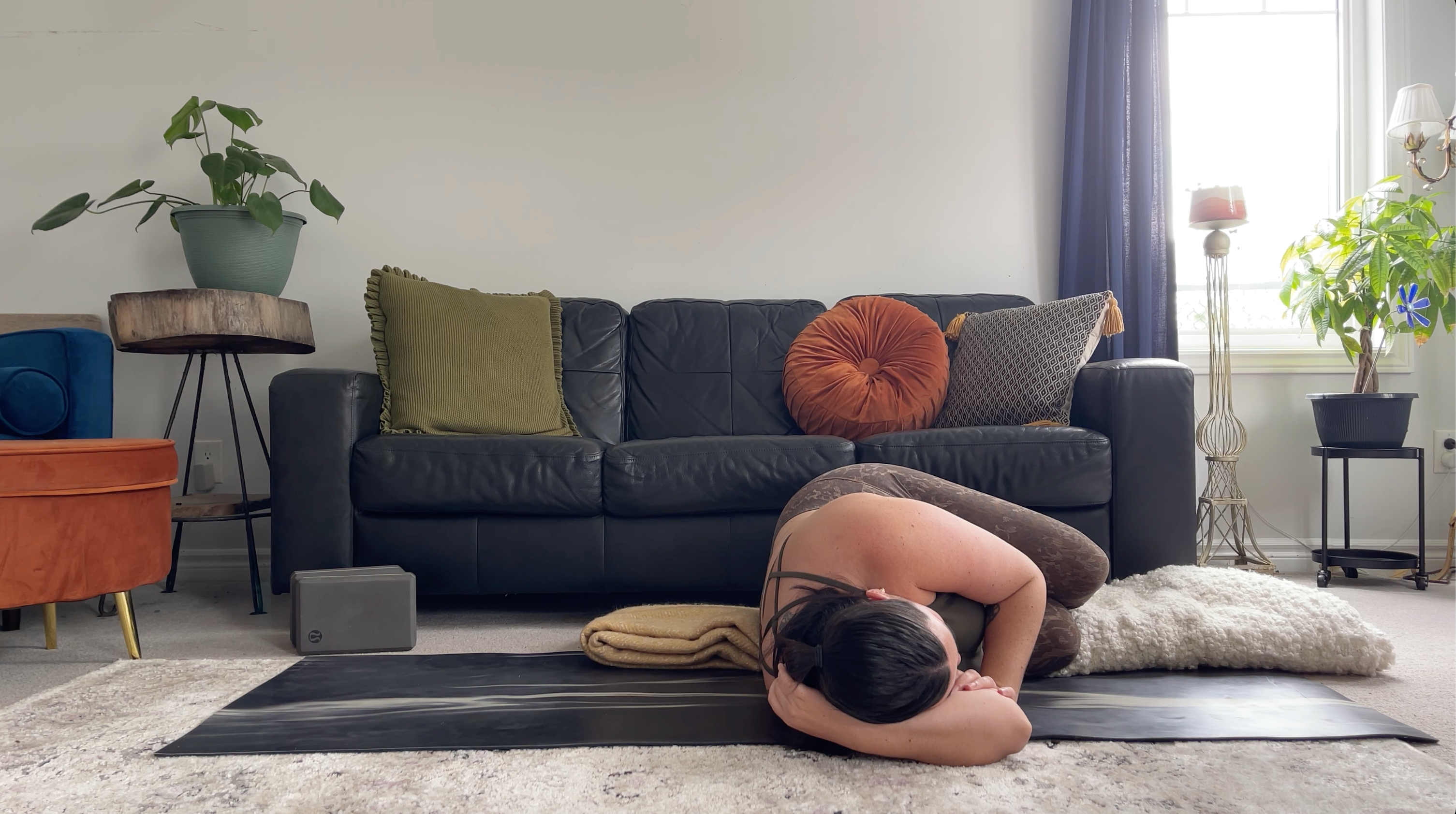 a woman in a restorative yoga pose, fetal pose