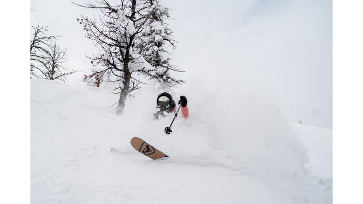Skier Sasha Dingle on skis while going downhill amid powder