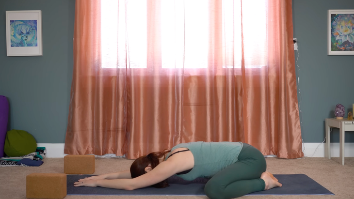 Yoga teacher practicing yin yoga for hips while stretching on a mat at home