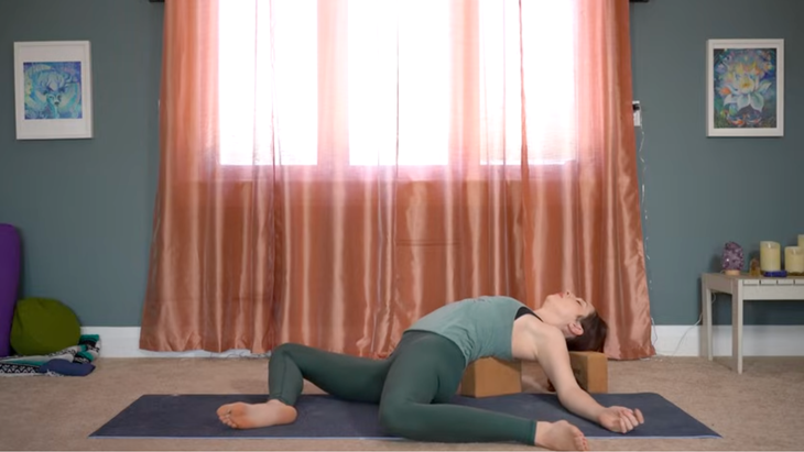 This Yin Yoga for Hips Routine Releases Unwanted Tension 3 Yoga teaching lying back on blocks placed on a yoga mat during stretches for hips