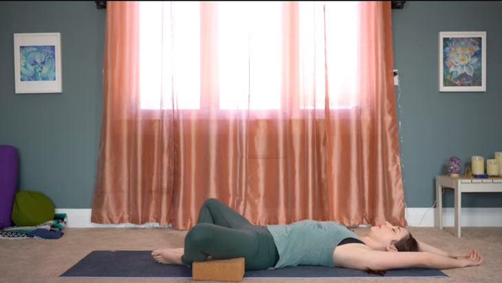 This Yin Yoga for Hips Routine Releases Unwanted Tension 5 Woman in Reclined Butterfly Pose stretching her tight hips and low back