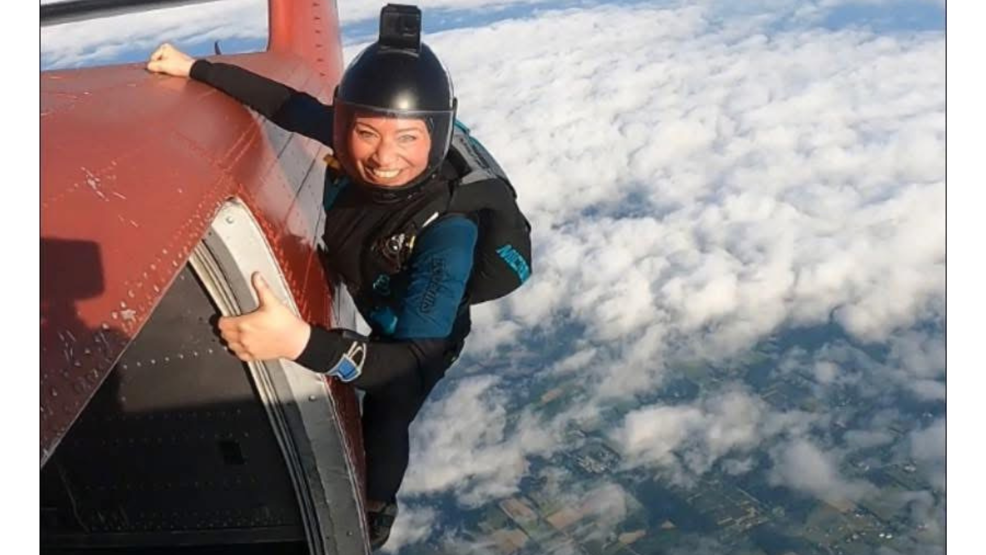 Yoga teacher Lisa Bermudez clinging onto the exterior of a plane while above clouds and farmland before she skydives