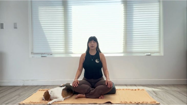 Woman sitting on yoga mat practicing three-part breath.