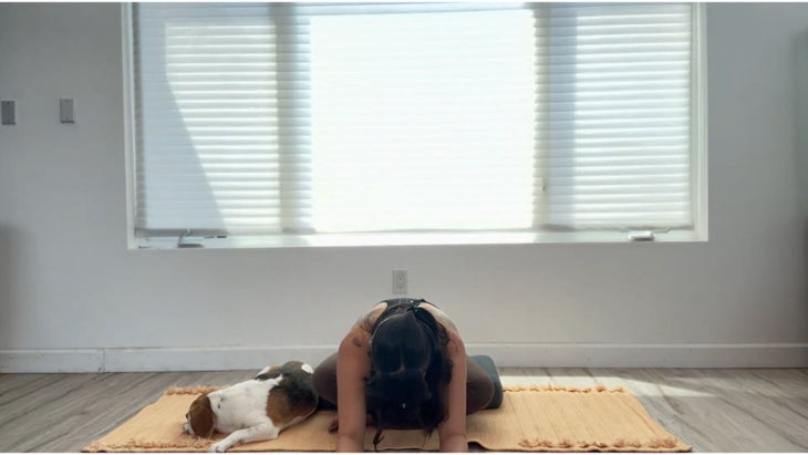 Woman practicing forward bend while legs are crossed.