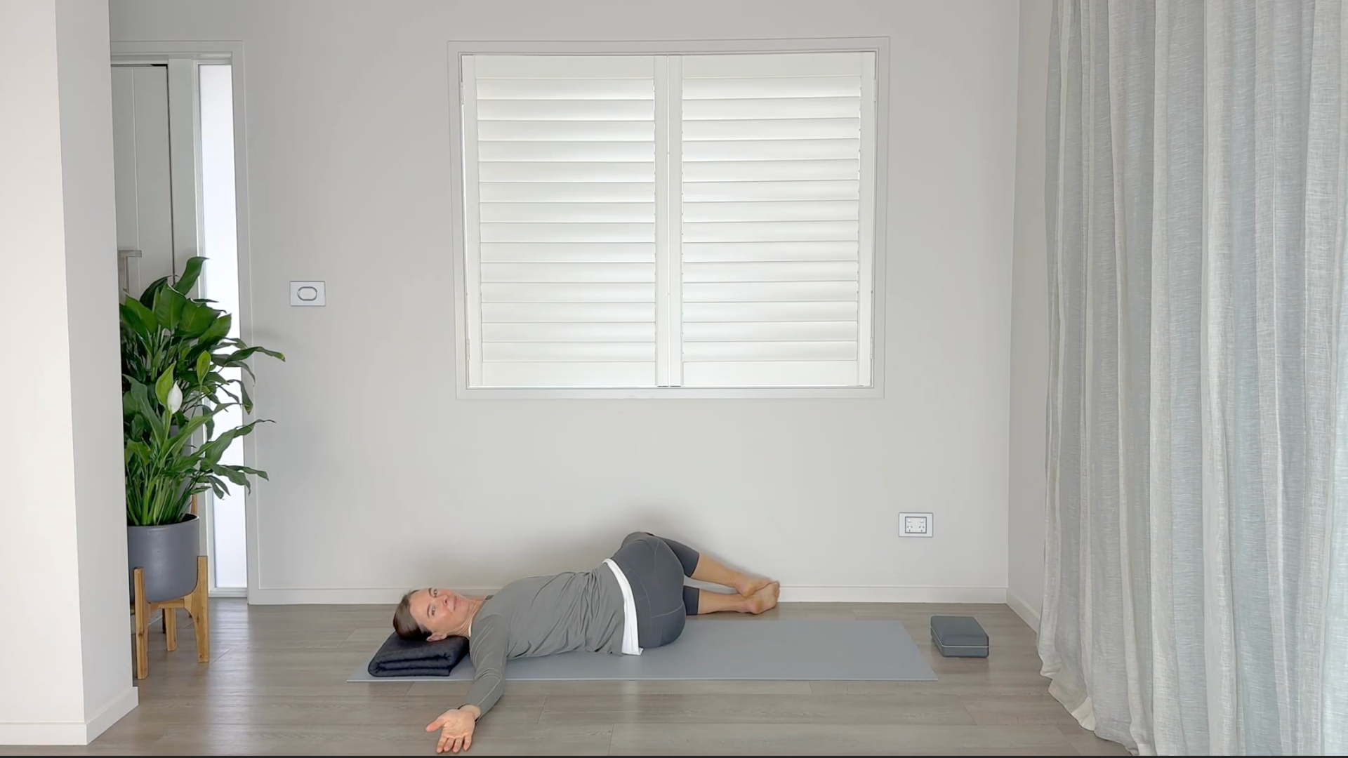 Yoga teacher lying on a mat practicing mid-back stretches