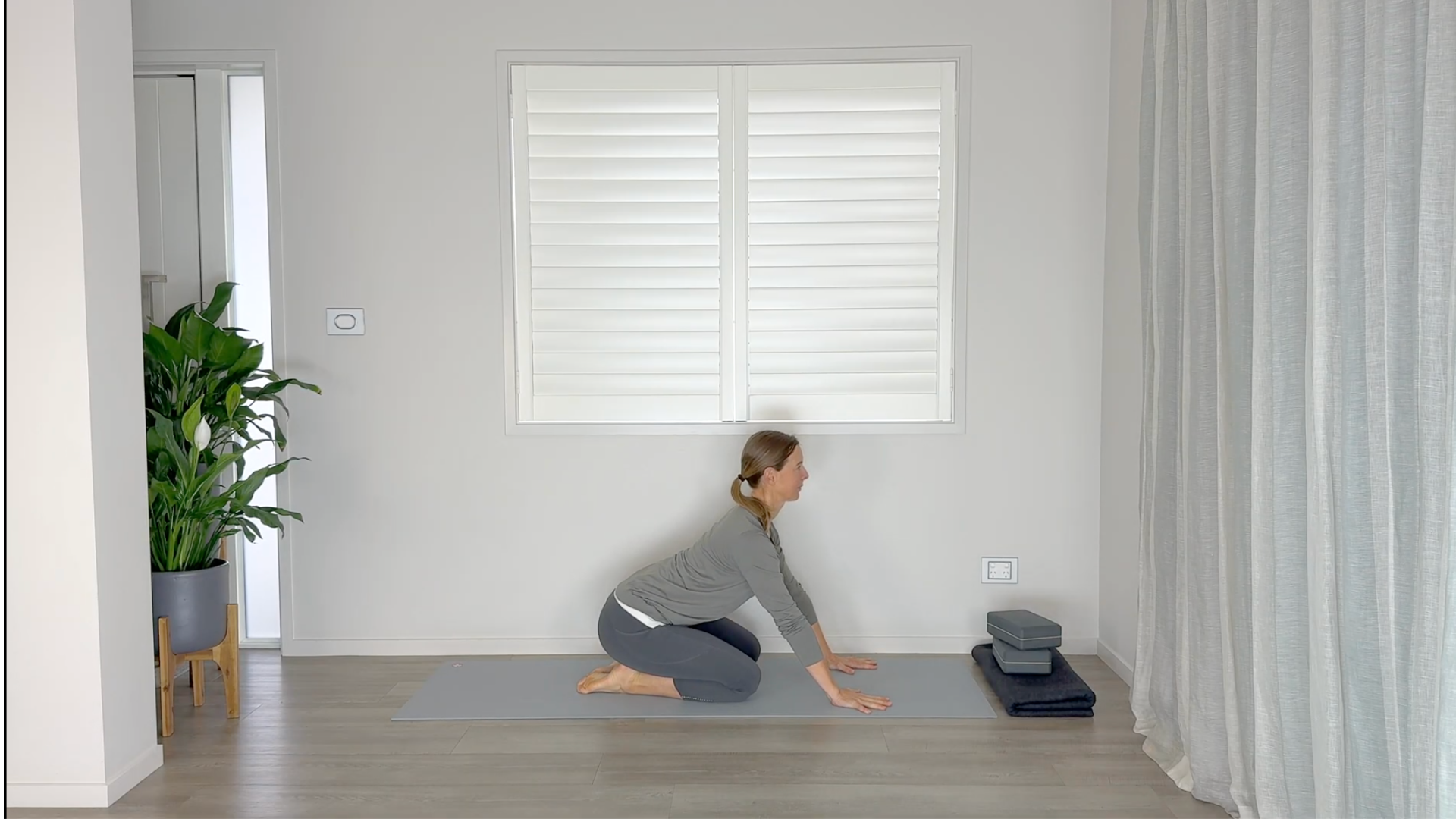 Yoga teacher kneeling on a yoga mat practicing Cat and Cow