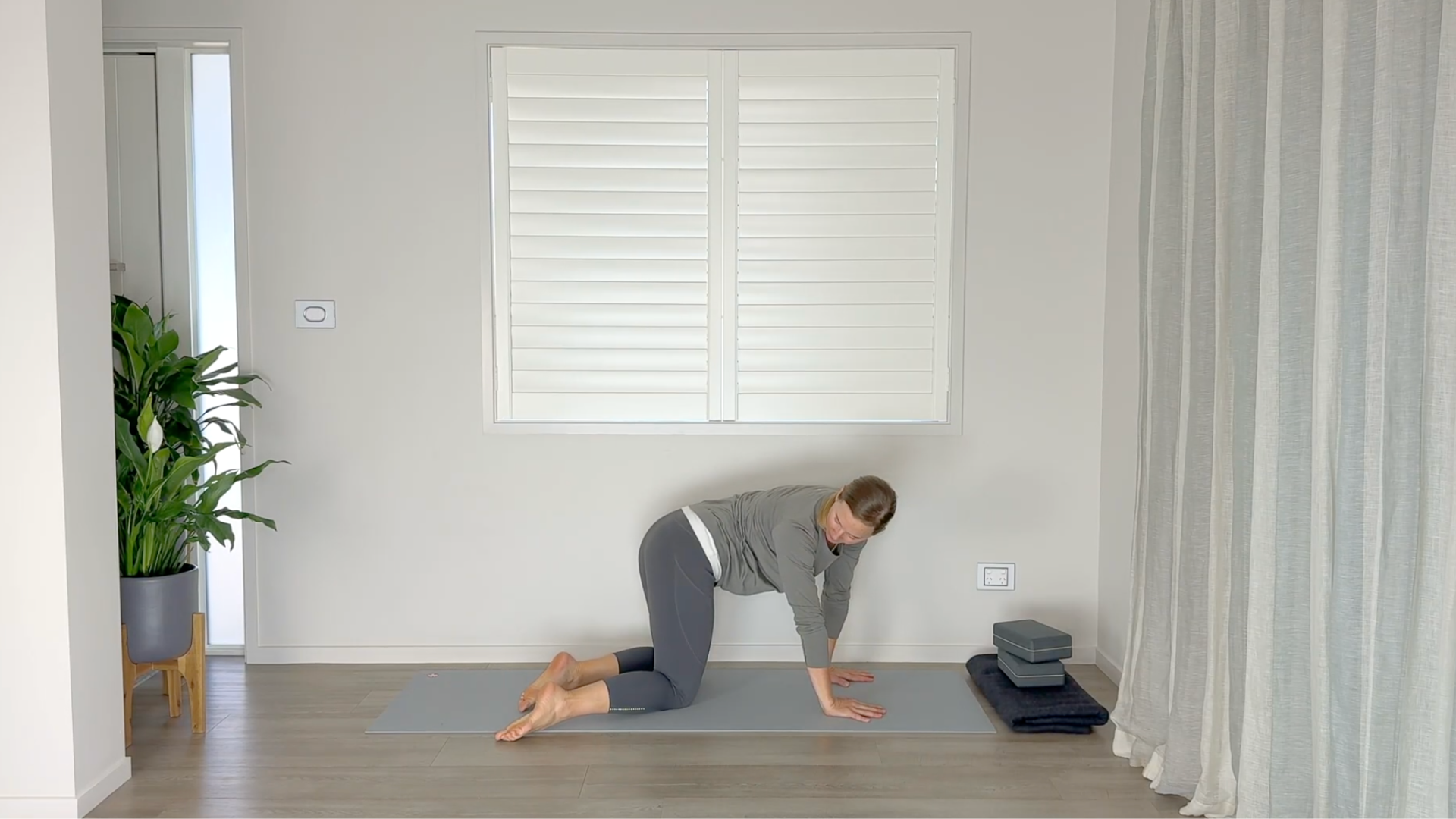 Yoga teacher kneeling on a yoga mat practicing mid-back stretches