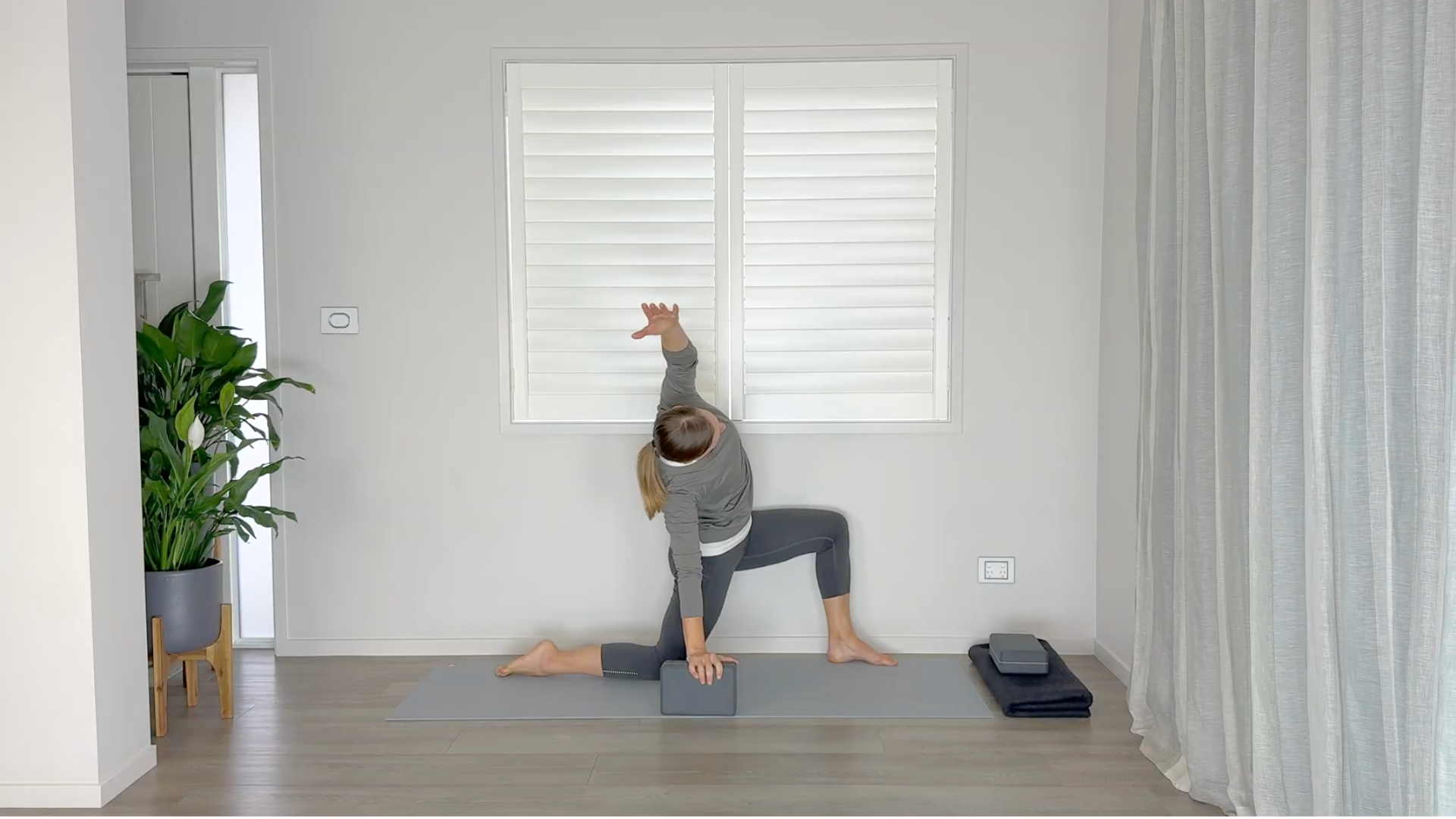 Yoga teacher kneeling on a mat practicing a side bend