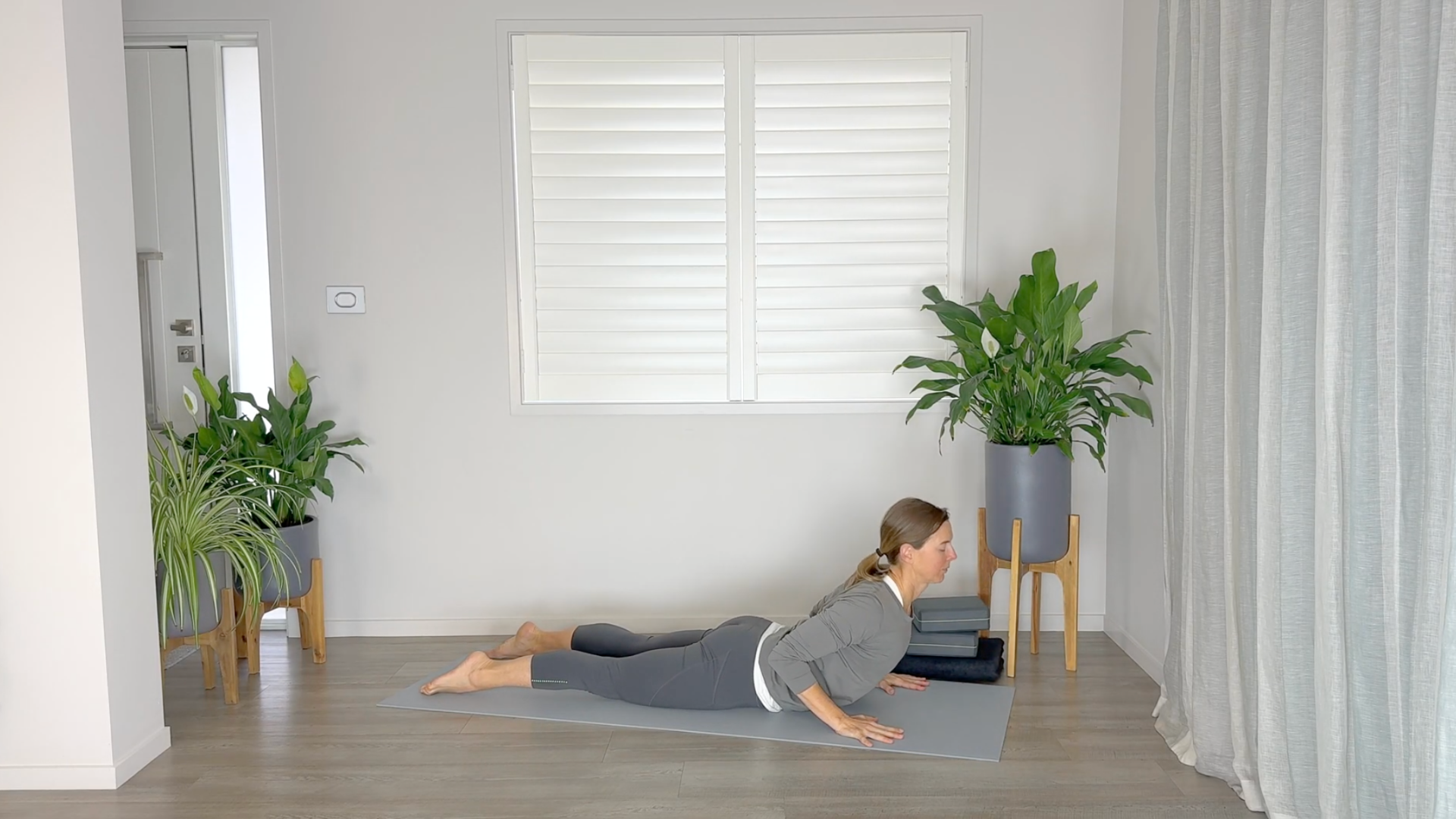 Yoga teacher lying on a yoga mat in Cobra Pose