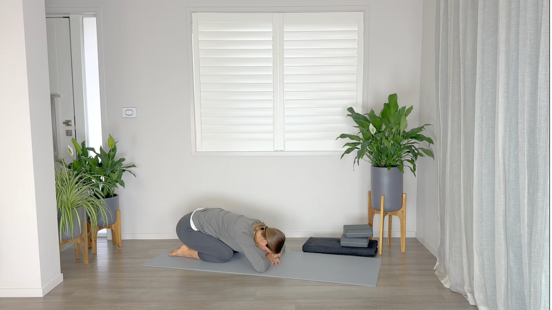 Yoga teacher practicing Child's Pose on a yoga mat