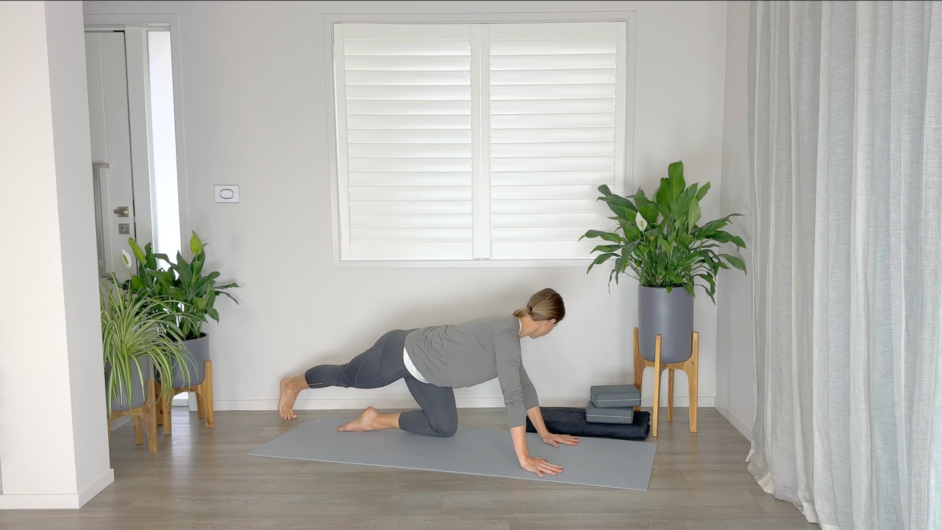 Yoga teacher kneeling on a yoga mat practicing an IT band stretch
