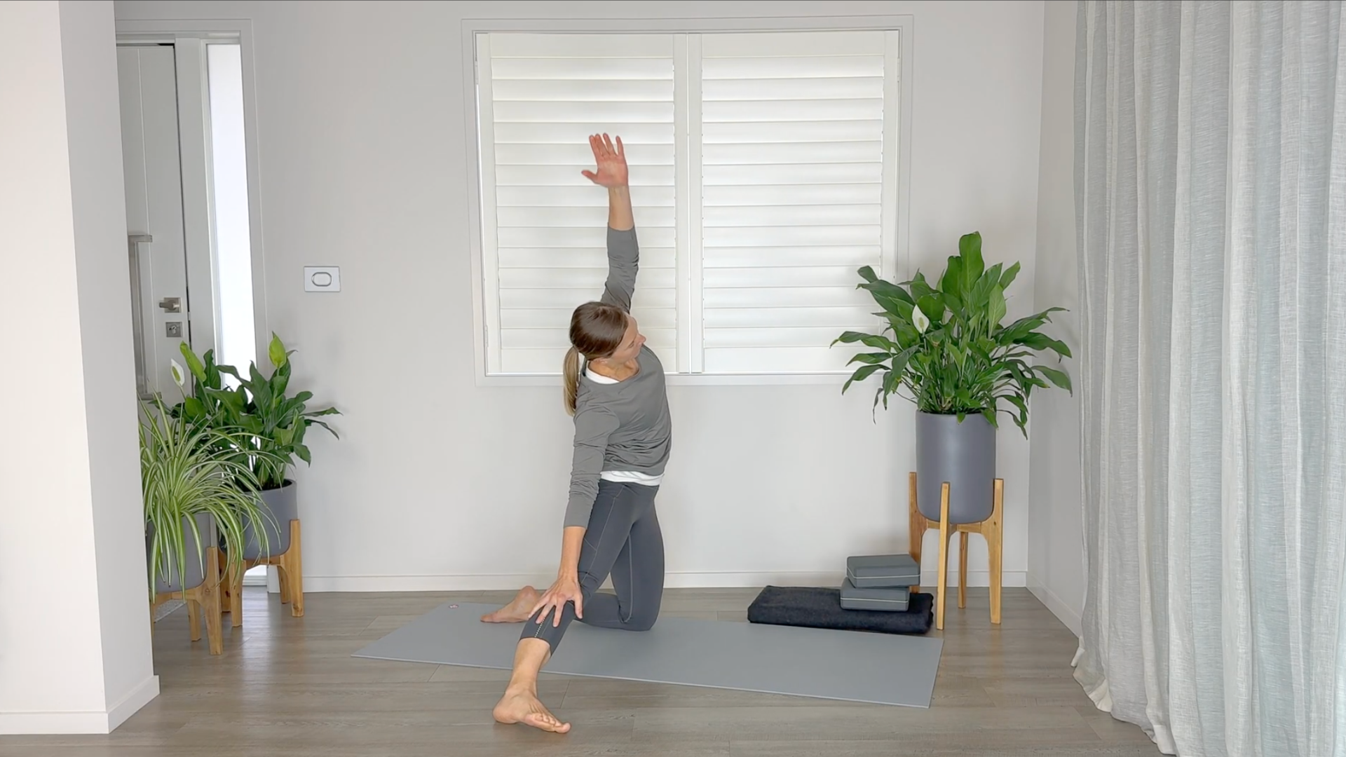 Yoga teacher kneeling on a mat practicing Gate Pose