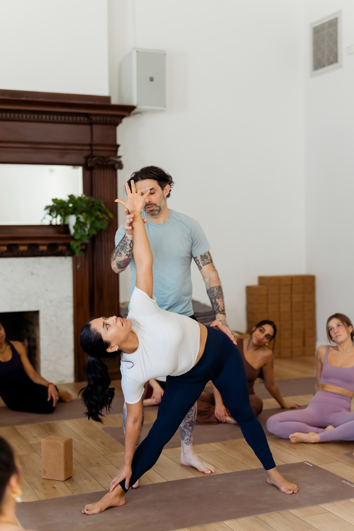 Teacher helping a student in Triangle Pose